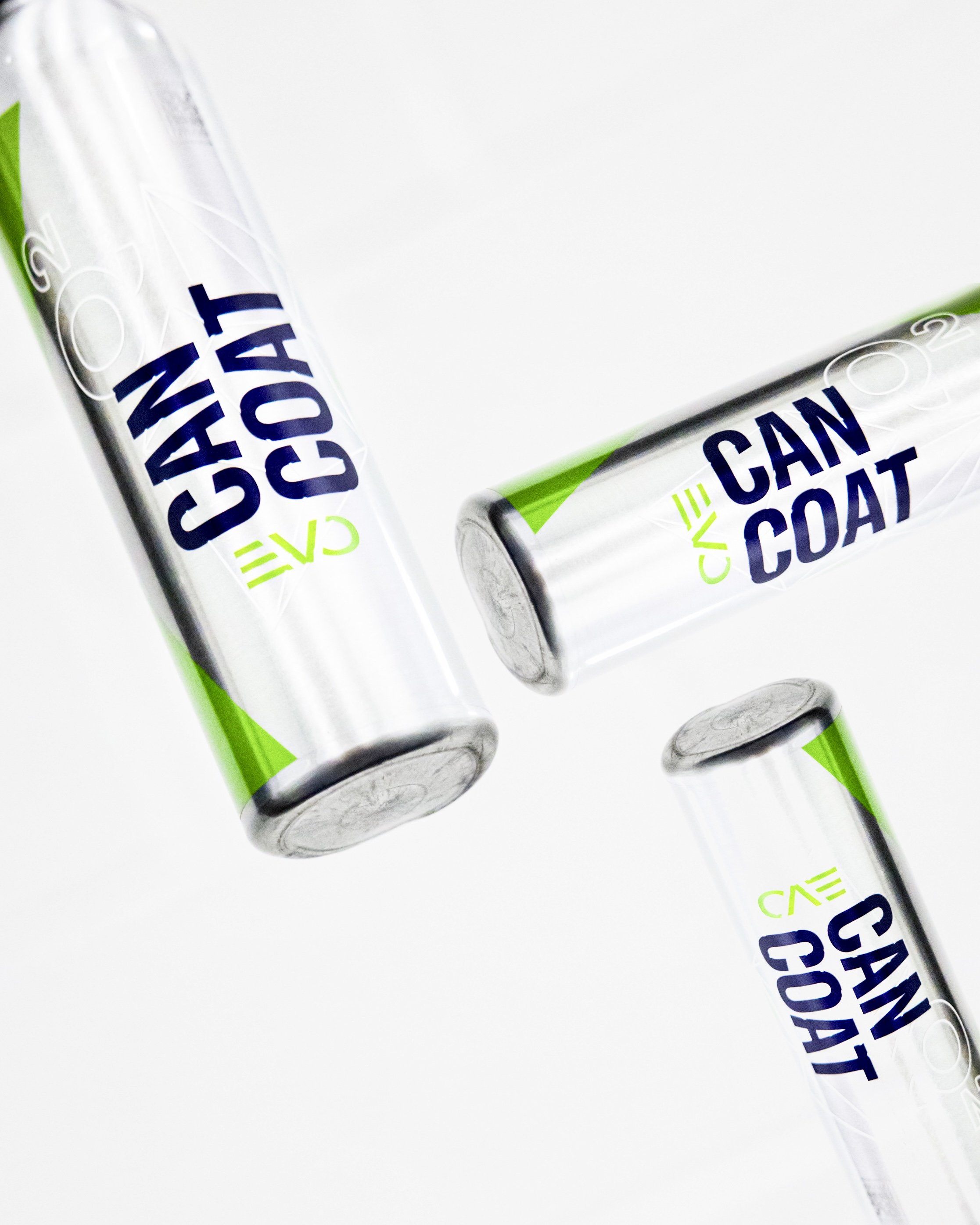 Three Gyeon Can Coat bottles tha have silver bodies, green accents, and blue and green text on a white background. They are positioned so it looks like they are falling in a elegant formation. The product is used to ceramic coat a car.