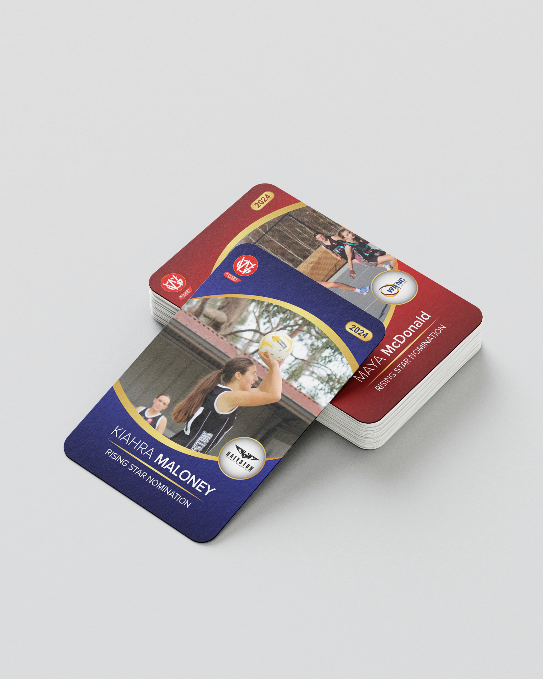 Stack of sports cards featuring two young female athletes, one preparing to shoot a netball and the other in mid-play during a game.