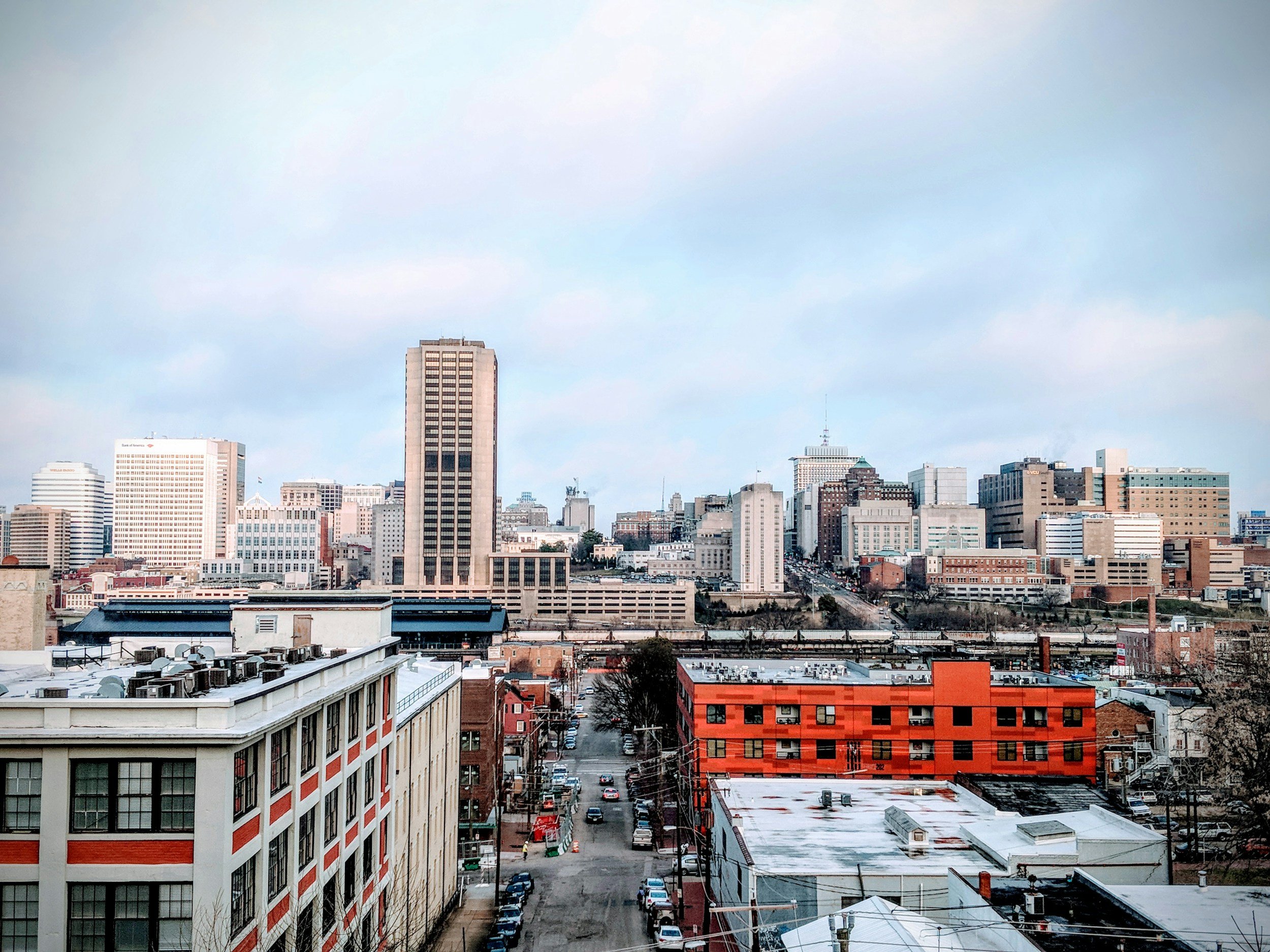 City skyline with a mix of tall and short buildings under a cloudy sky.