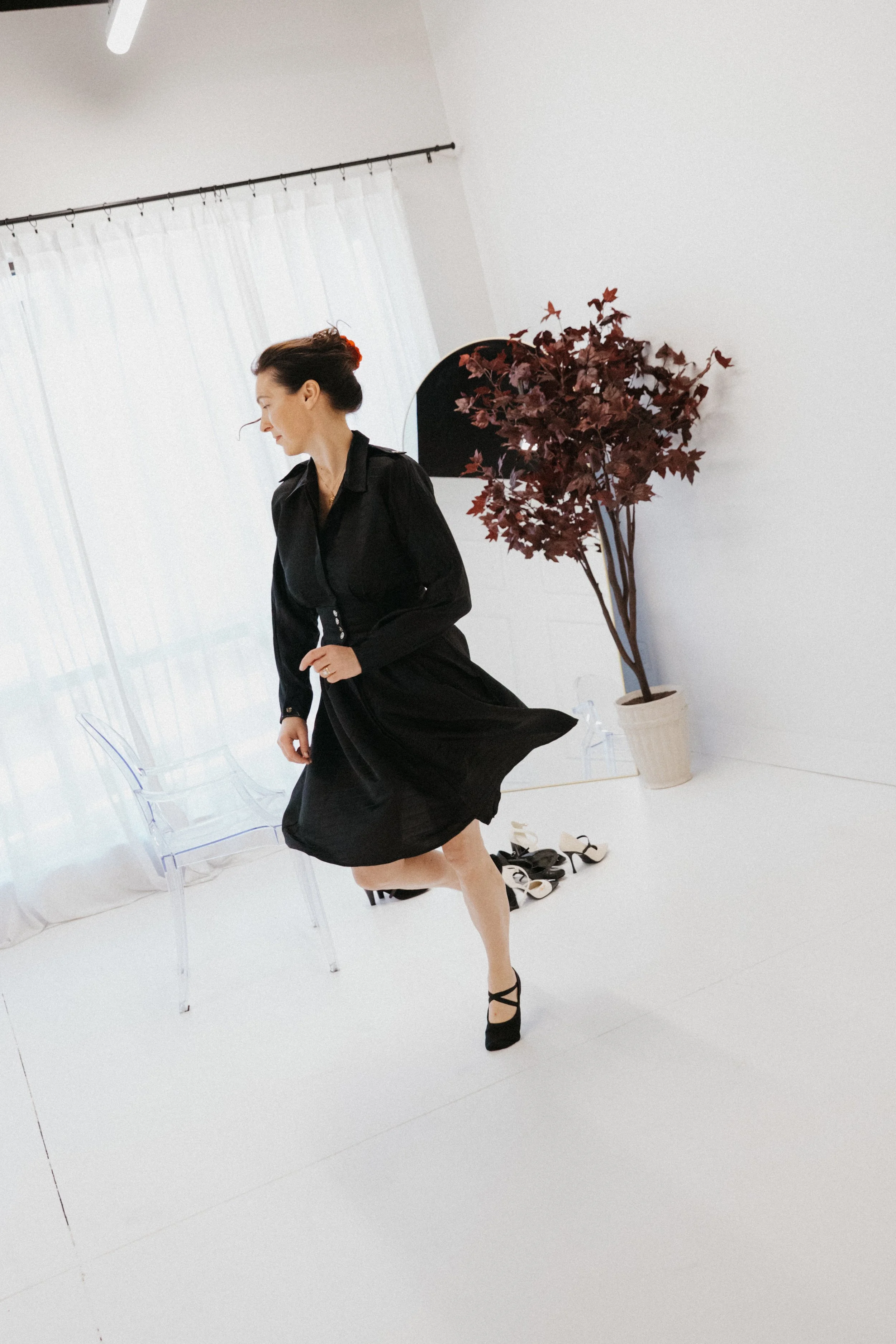 Dr. Kat moving through a bright minimalist studio in a flowing black dress, reflecting movement, lightness, and the feeling of reconnecting with yourself and your energy again.
