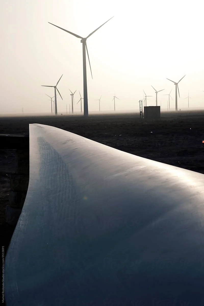 A landscape of a wind farm with multiple wind turbines on a foggy day, and a large metal structure in the foreground.
