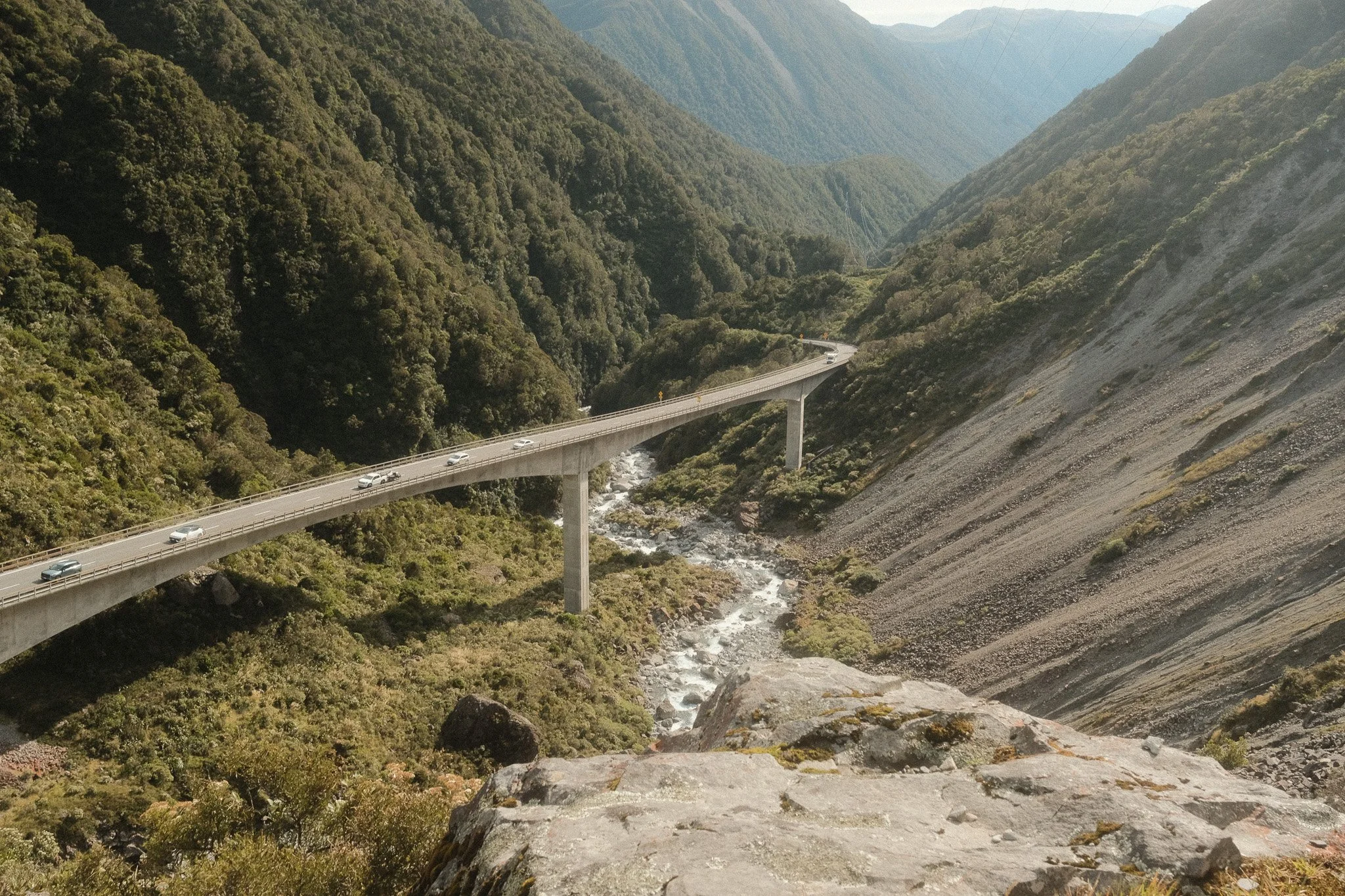 A bridge over a river in a green, mountainous landscape.