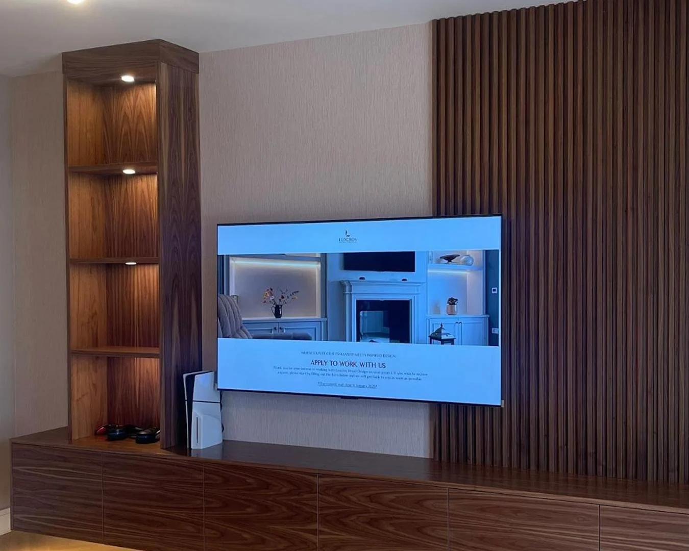 A sleek, asymmetrical floating cabinet crafted with walnut veneer exteriors keeps the room open and inviting, with push-to-open doors that keep all essentials in order. Open display shelving with subtle spotlighting sits to the left, balanced by slat