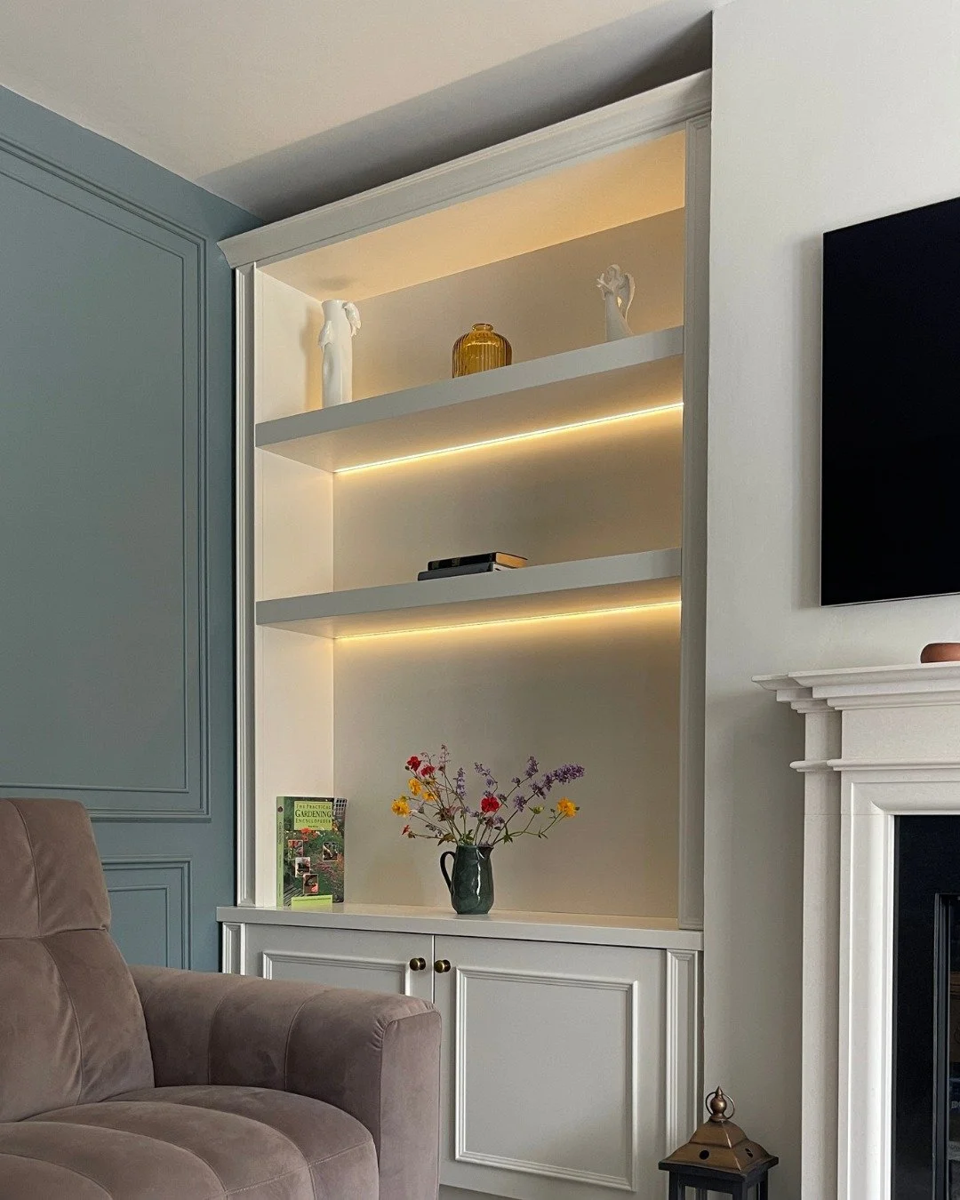 In a room like this, the alcoves naturally become part of how the space is used. Cabinets finished in Colourtrend&rsquo;s &lsquo;Temperance&rsquo; with oak interiors keep items organised and out of sight, while floating shelves with recessed LED stri