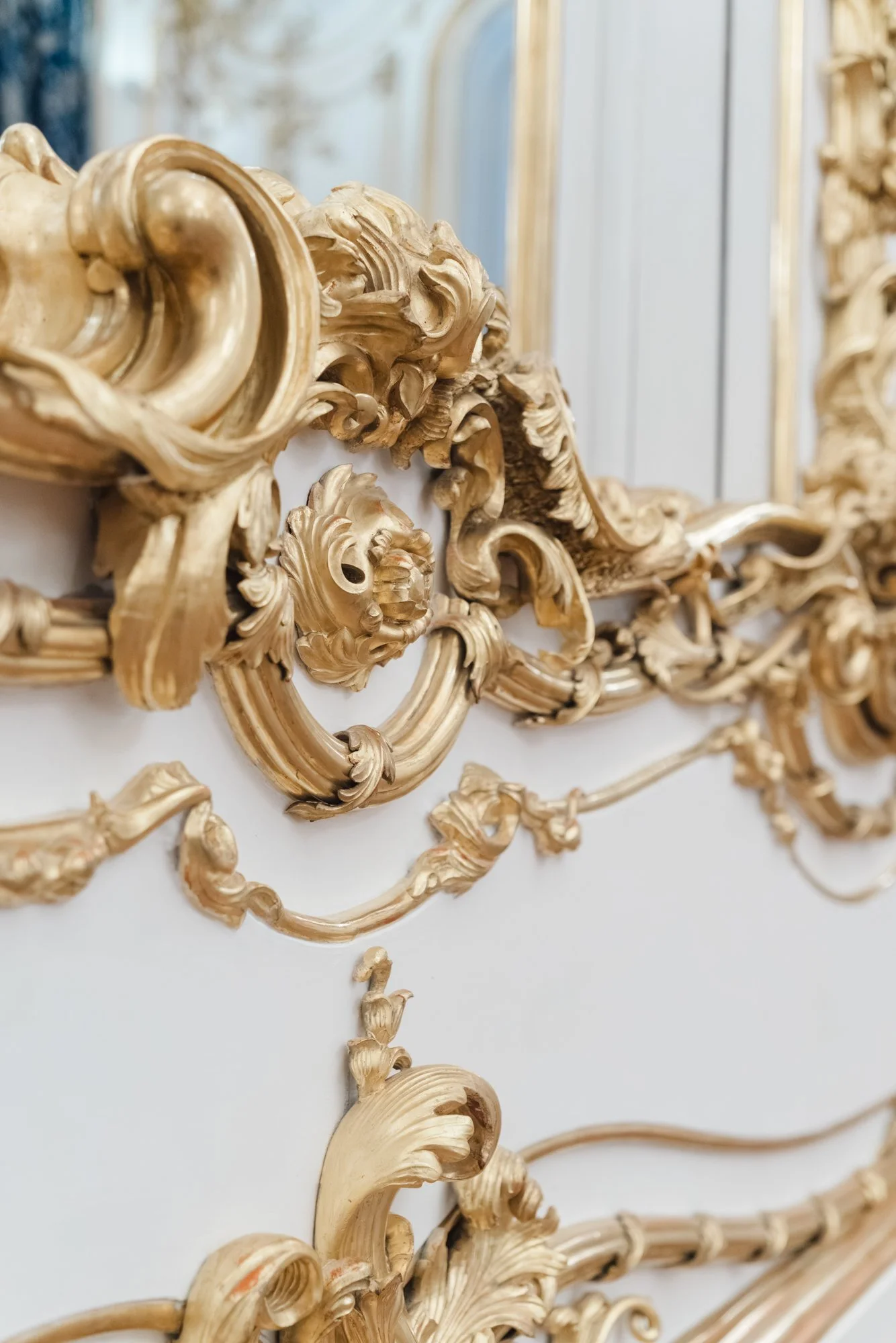 Close-up of a decorative gold-leaf ornate carved frame with intricate scrollwork and floral details.