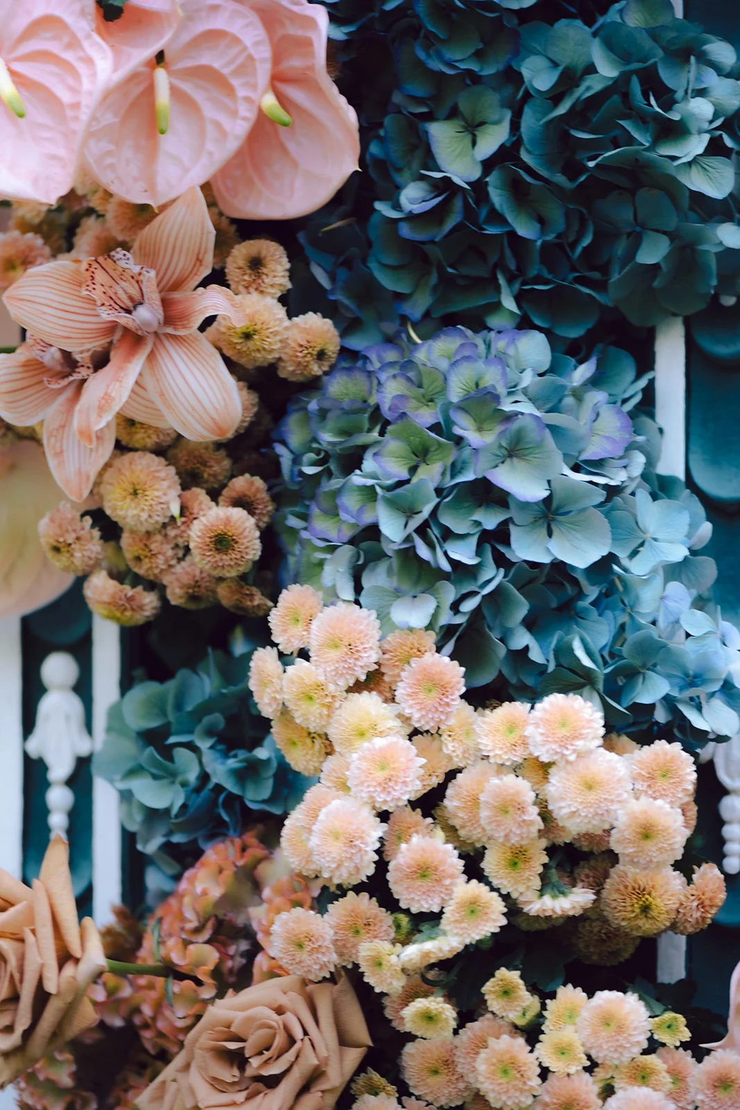 A colorful arrangement of mixed flowers, including pink lilies, peach chrysanthemums, purple and green hydrangeas, and roses.