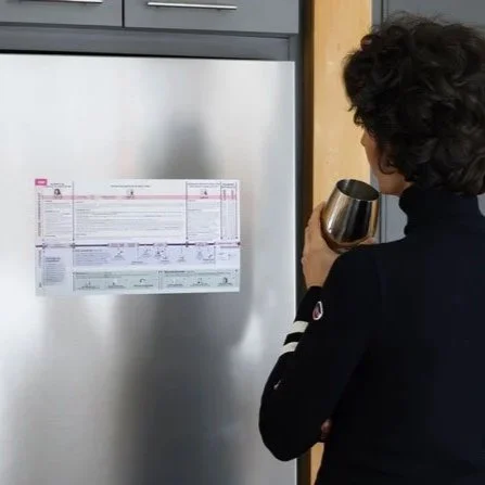 Personne consultant une frise chronologique papier de l’histoire de France accrochée au frigo pour un usage quotidien