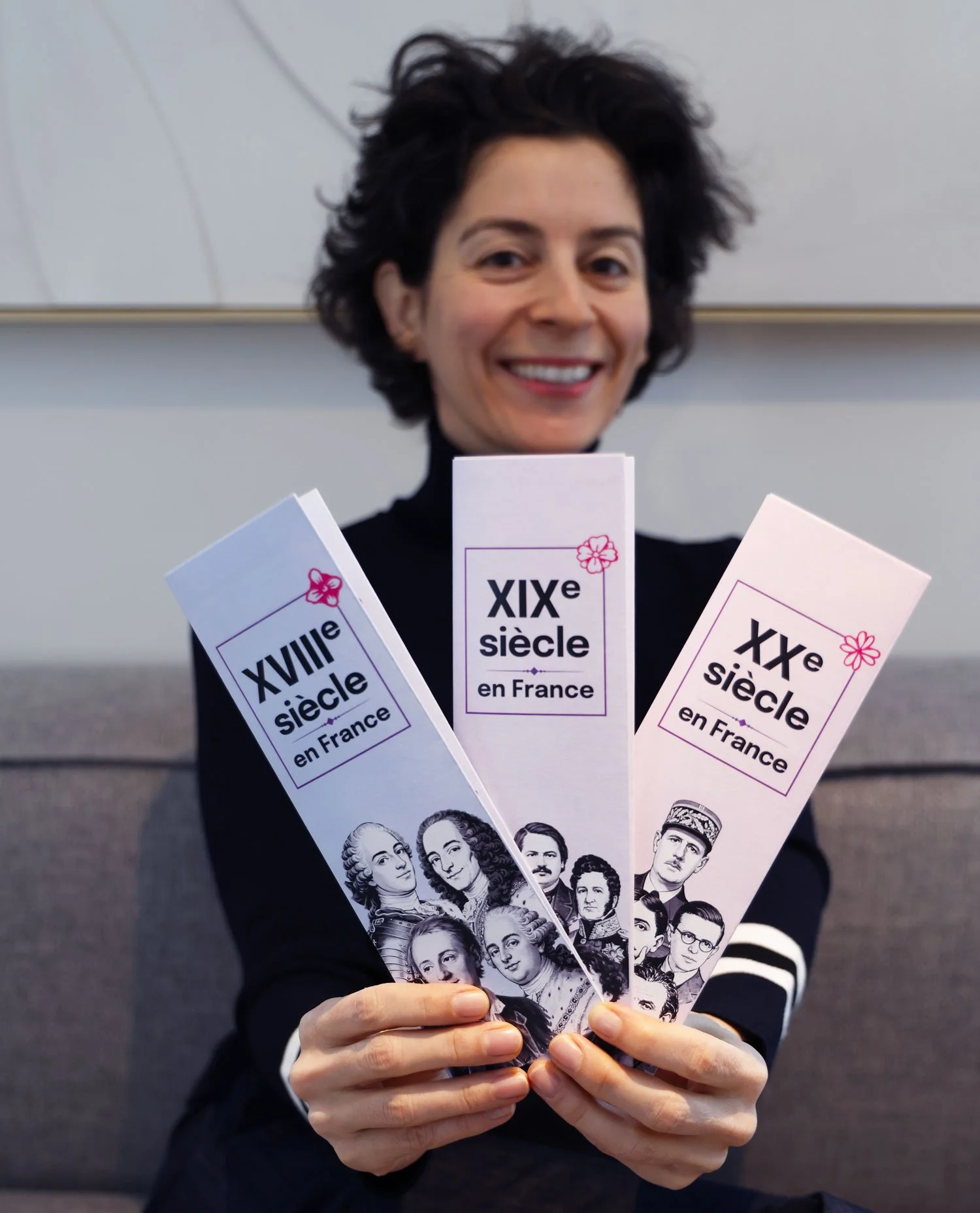 Personne tenant les trois frises chronologiques papier 18e, 19e et 20e siècles, montrant les couvertures et l’apparence générale du produit