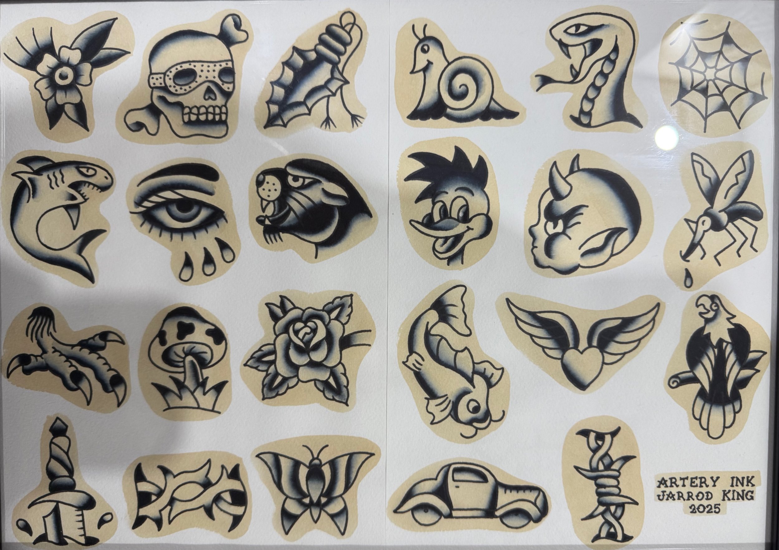 Sheet of tattoo-style illustrations in black and gray, each with a beige background, including a flower, skull, leaf, snail shell, snake, spider web, shark, eye, rooster, unicorn, butterfly, and various other creatures and symbols. A small label in the bottom right corner reads: "ARTERY INK, JARROD KING, 2025".