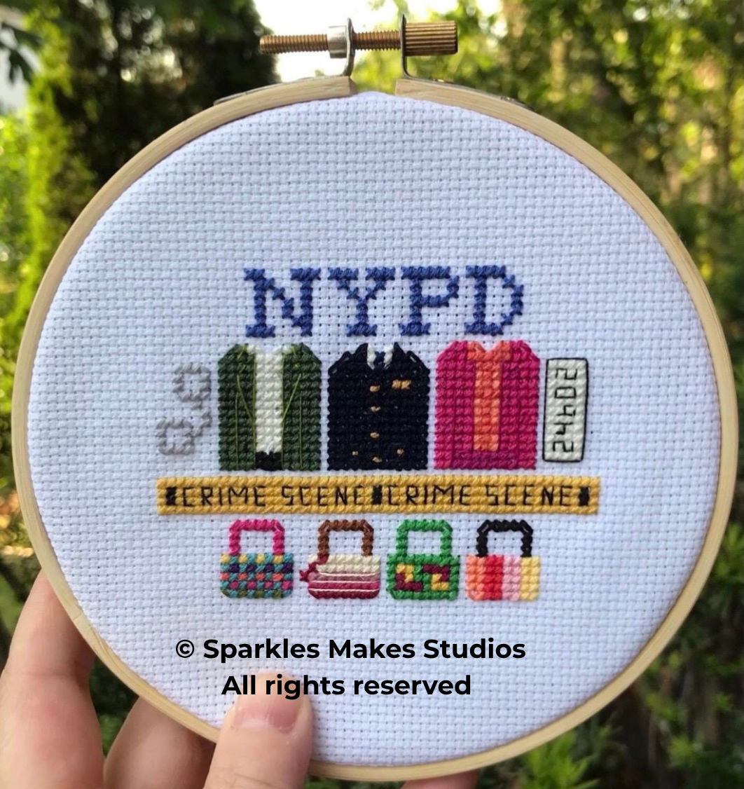 Cross-stitched artwork of the NYPD badge with three handbags, a yellow banner that reads 'CRIME SCENE', and a small sign with 'FMO3'.