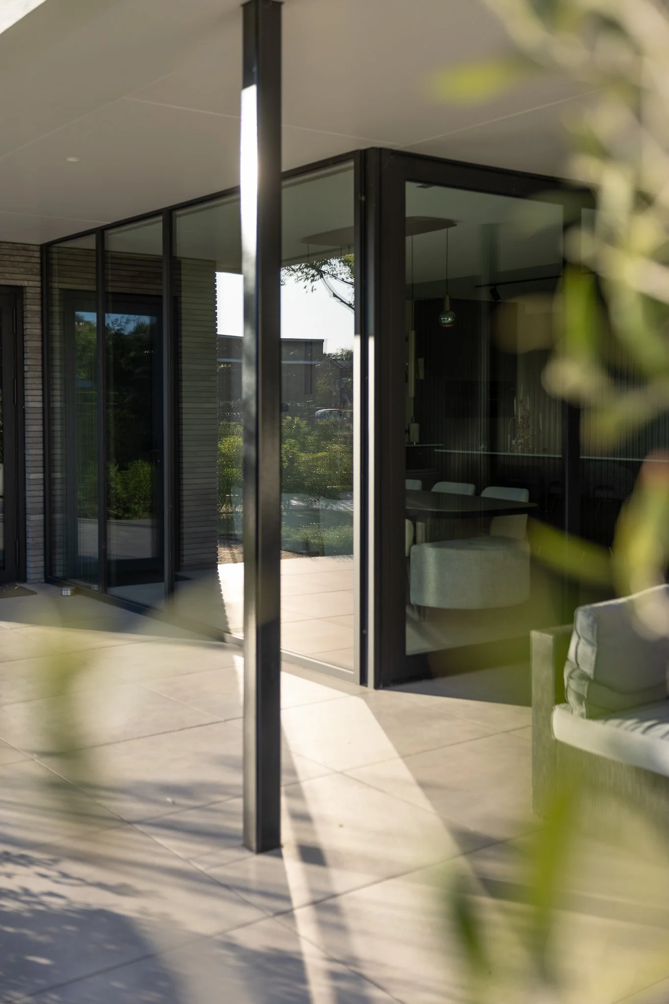 Grey brick exterior wall with black-framed windows and soft tree shadows in the morning light