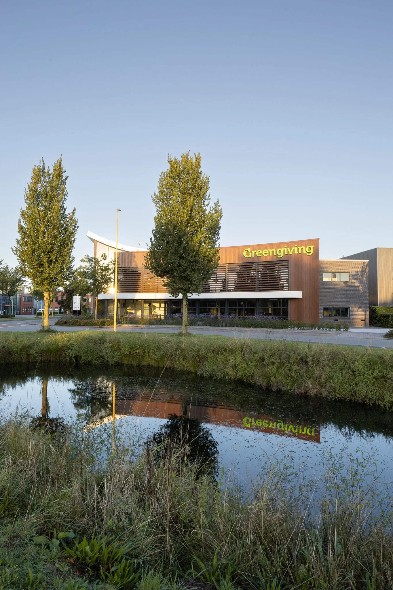 Contemporary Greengiving office reflected in the water beside a landscaped business park