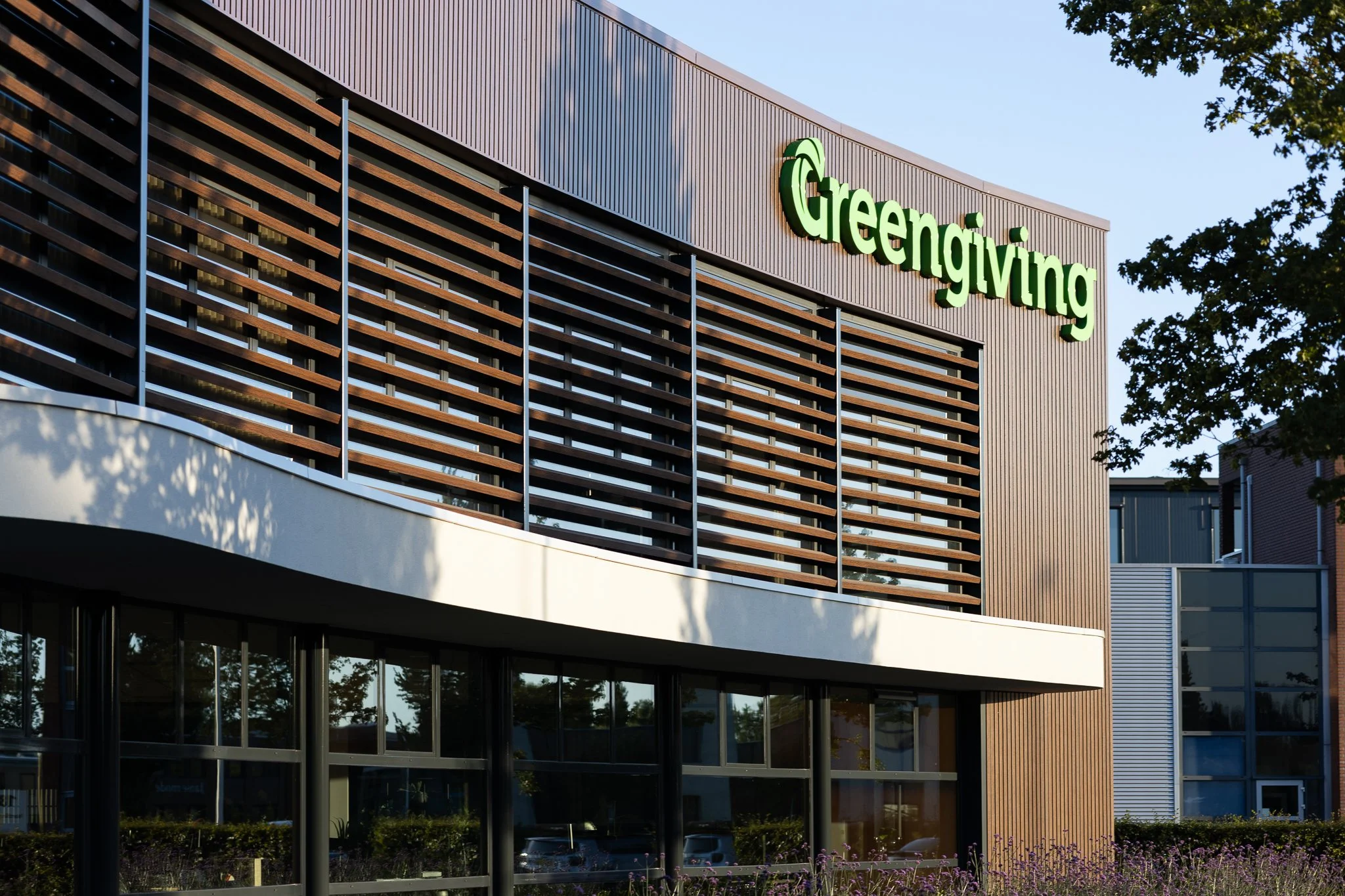Front façade of the Greengiving office with wooden sunshades and purple landscaping