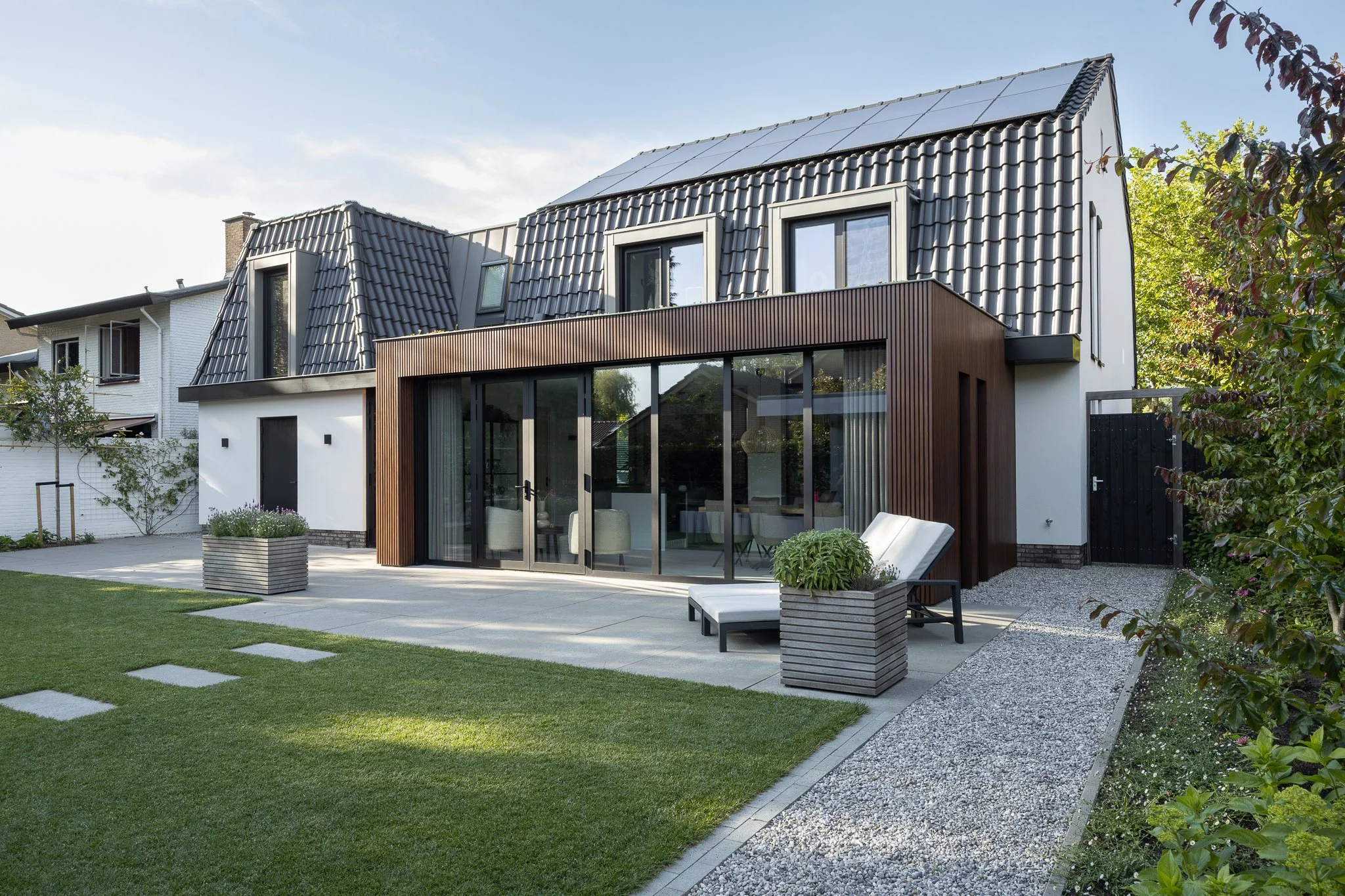 Wide exterior view of a contemporary timber and glass extension with a neatly landscaped garden