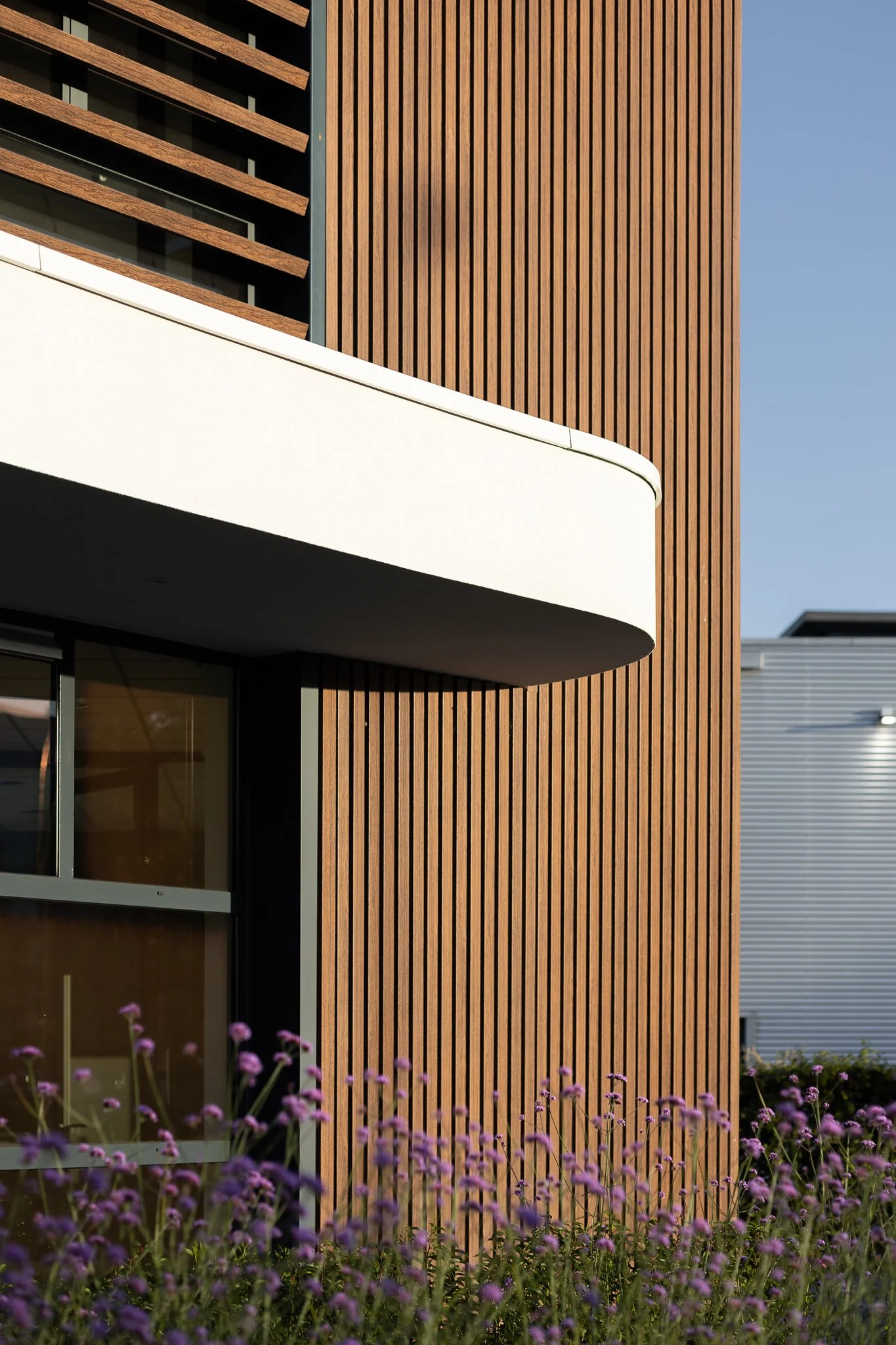 Timber façade and horizontal sunshades captured in soft golden morning light