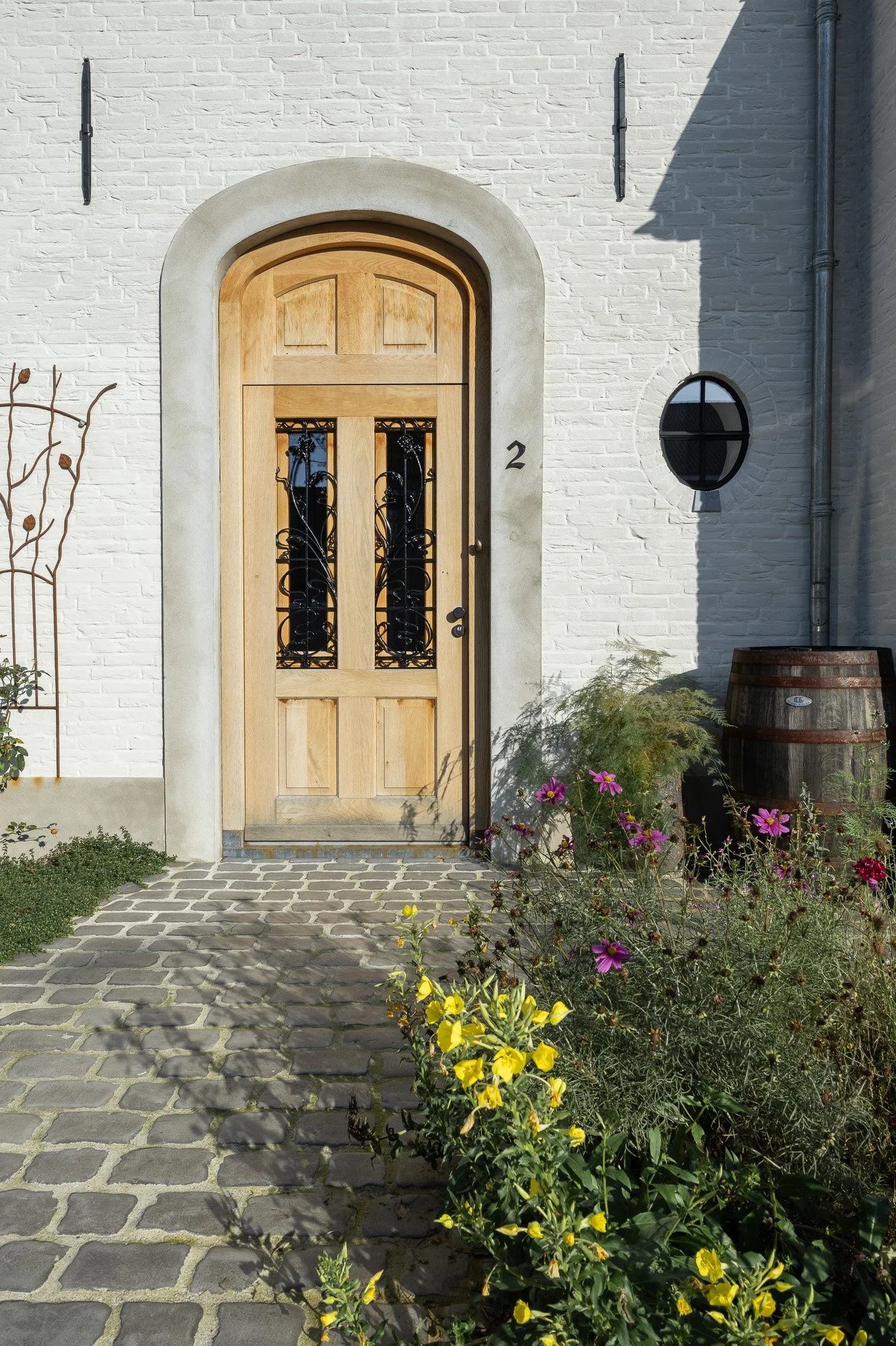 Side elevation of a white brick home with a dark tiled roof and grey entrance door