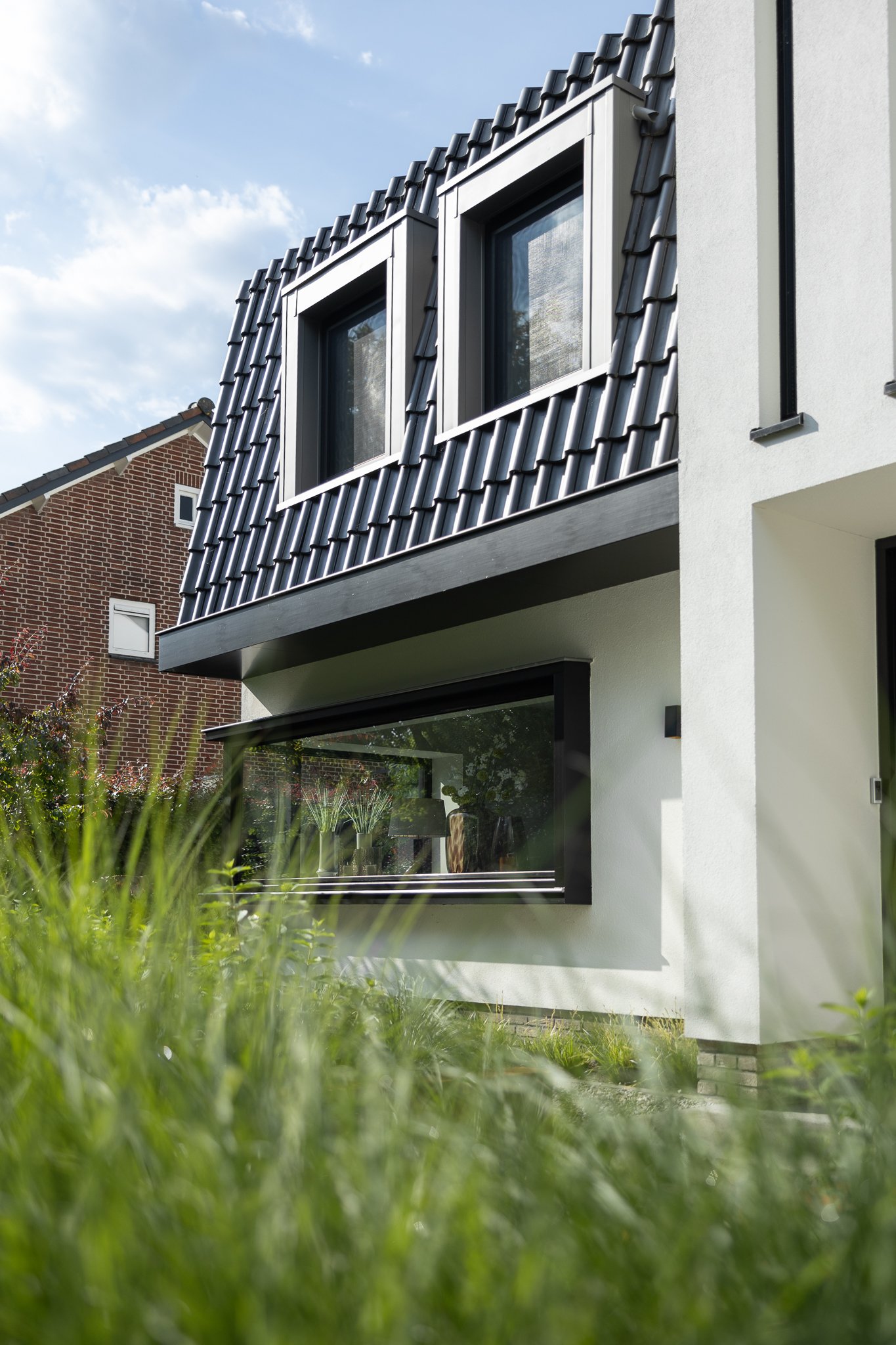 Black-framed bay window and dormer windows set into the dark tiled roof of a modern villa
