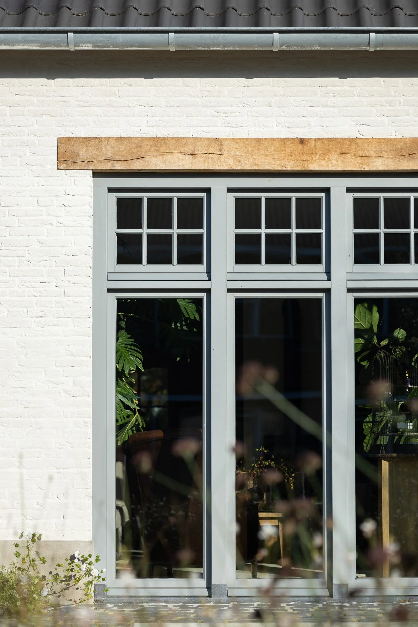Front elevation of a white brick home with an arched wooden entrance and landscaped garden