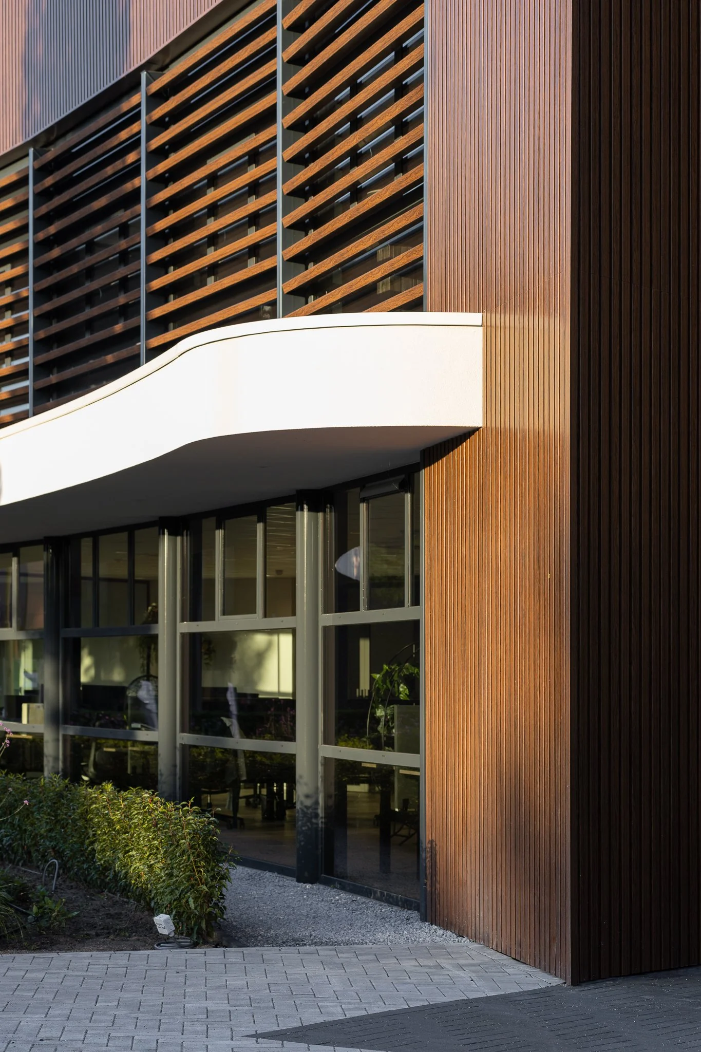 Close exterior view of the Greengiving office with horizontal wooden sunshades and glass windows