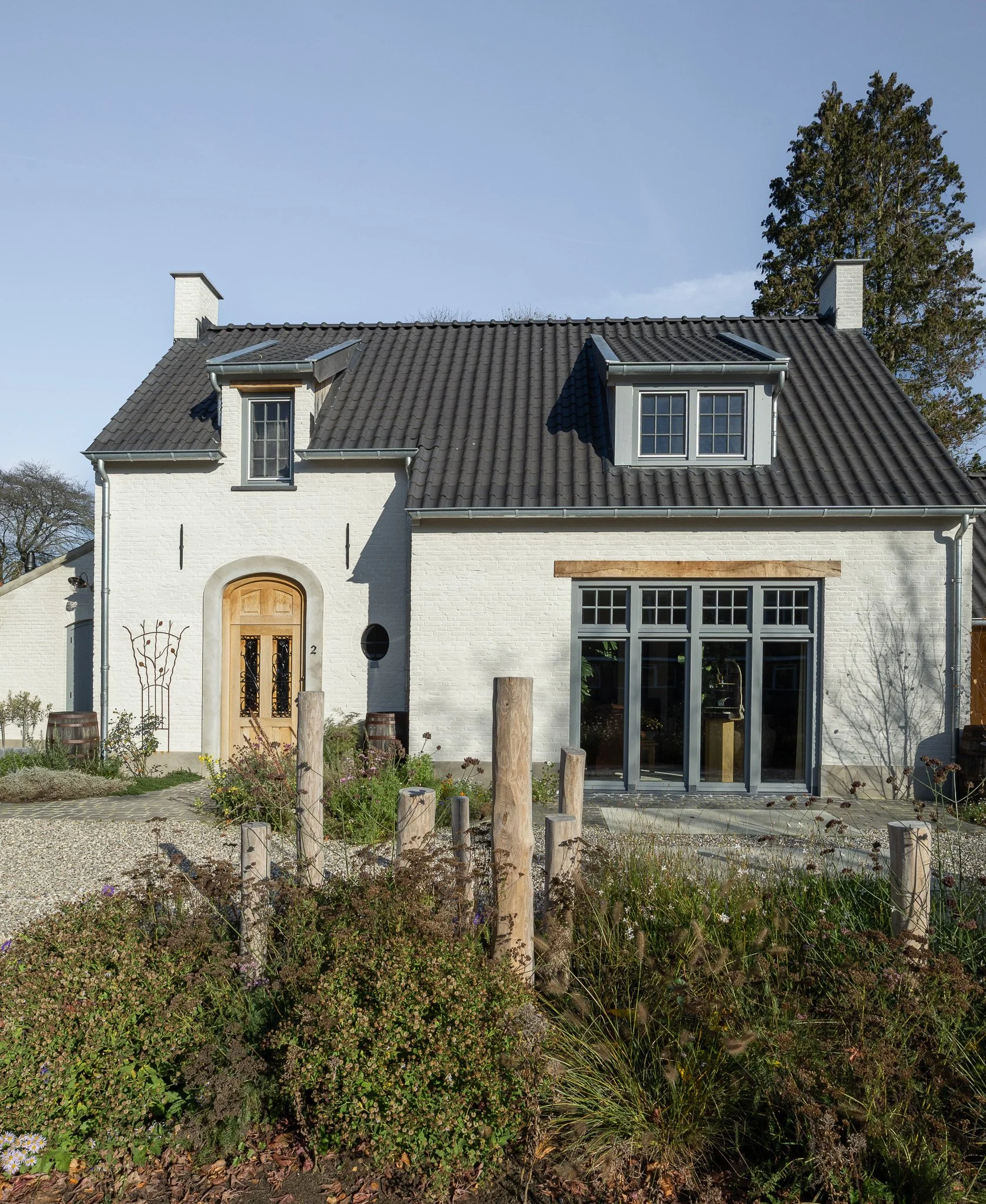 Elegant white brick home with a dark tiled roof, autumn garden and gravel driveway