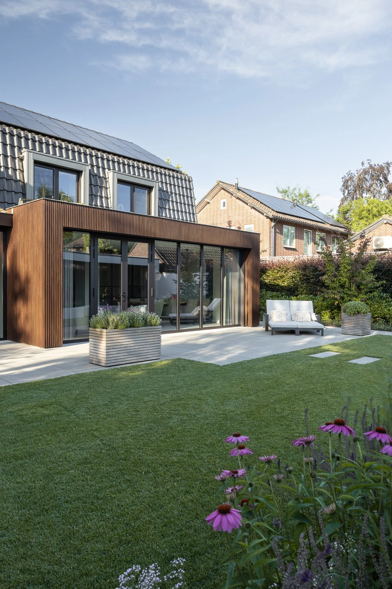 Landscaped garden with purple flowers surrounding a modern timber and glass extension
