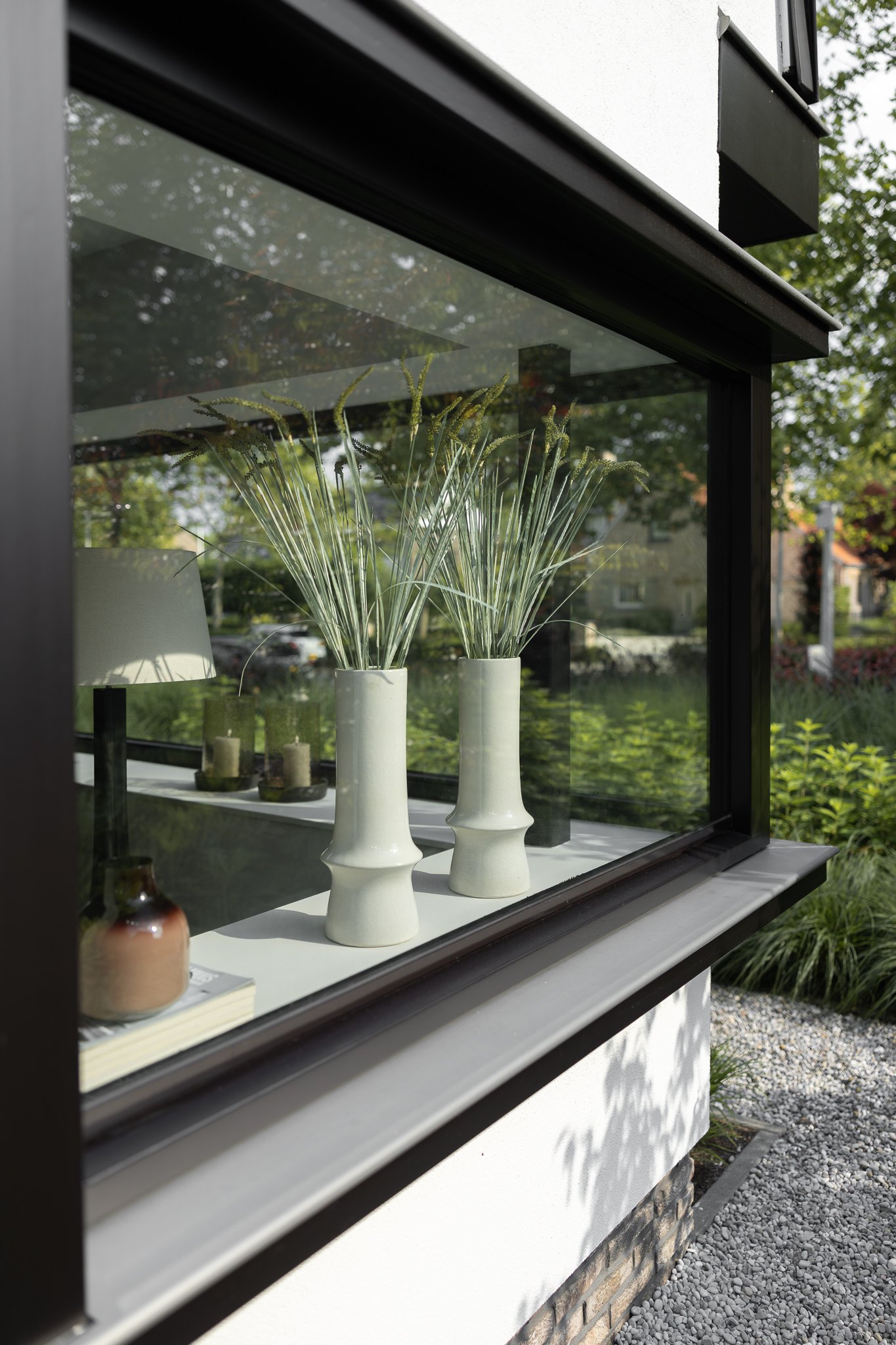 Black-framed bay window with decorative white vases overlooking the landscaped garden