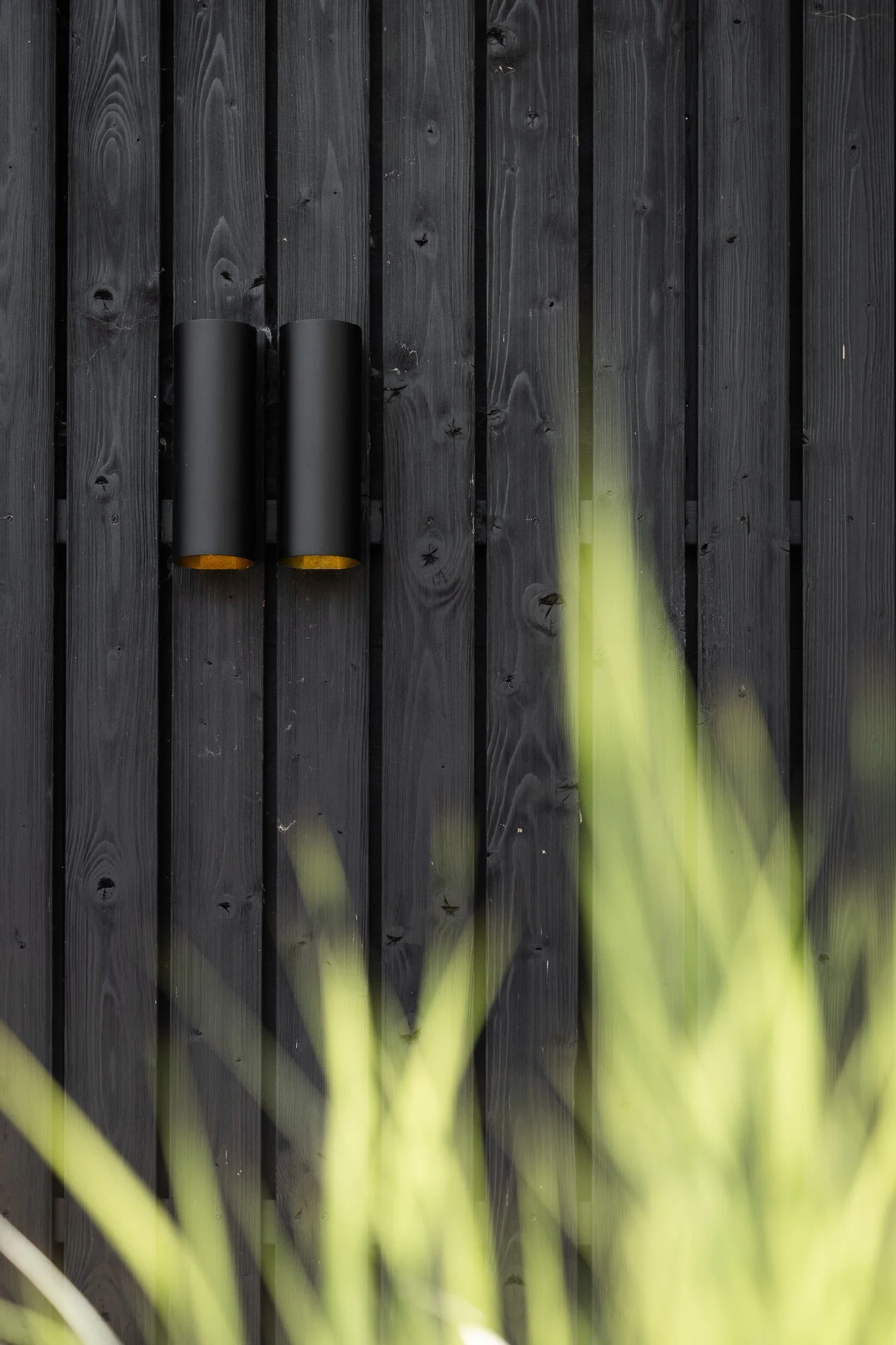 Minimal black wall lights mounted on vertical timber cladding
