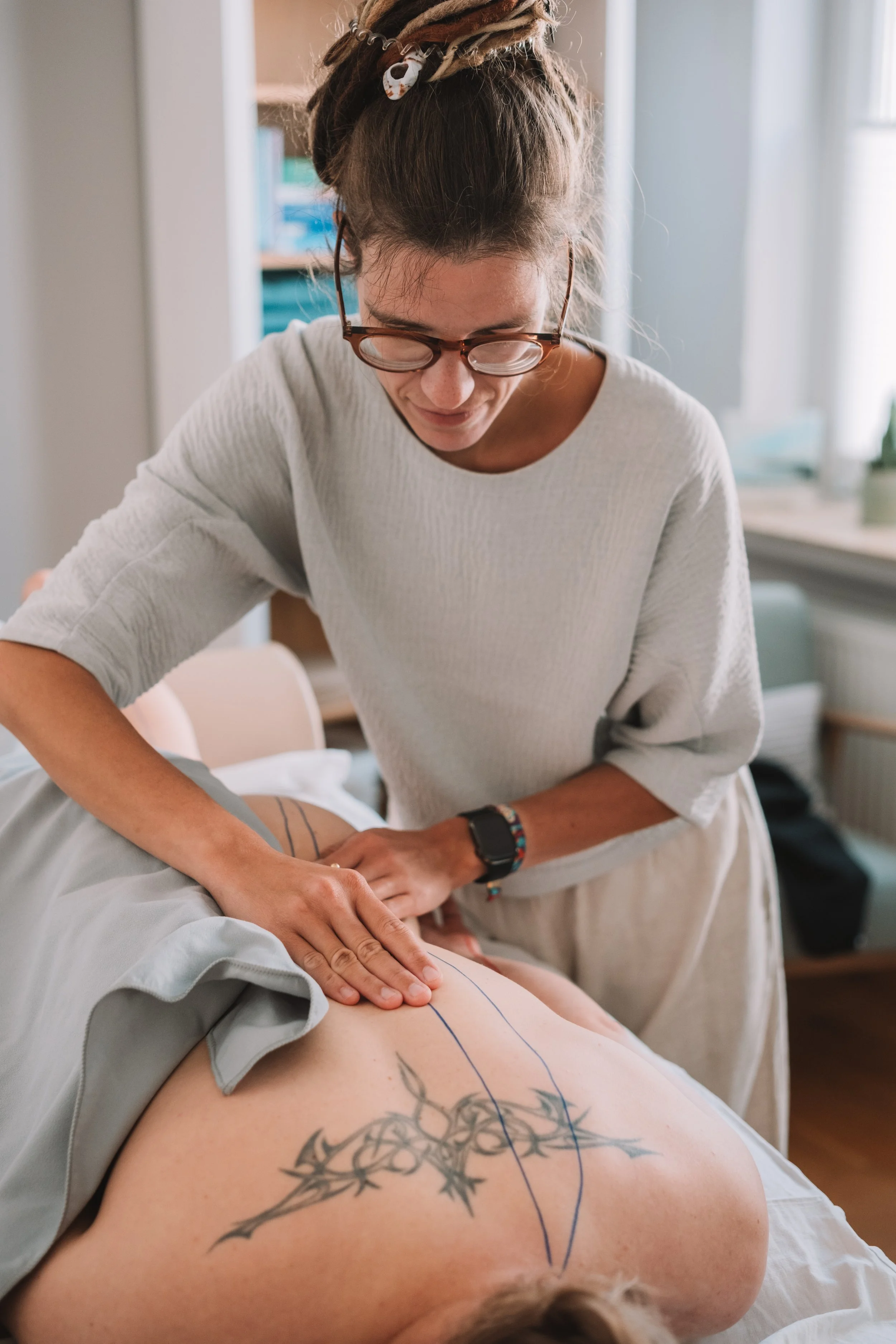 Linda Zimmermeier (Heilpraktikerin für Physiotherapie aus Gütersloh) führt eine Akupunkt Massage nach Penzel auf dem Blasenmeridian auf dem Rücken einer Patientin durch.