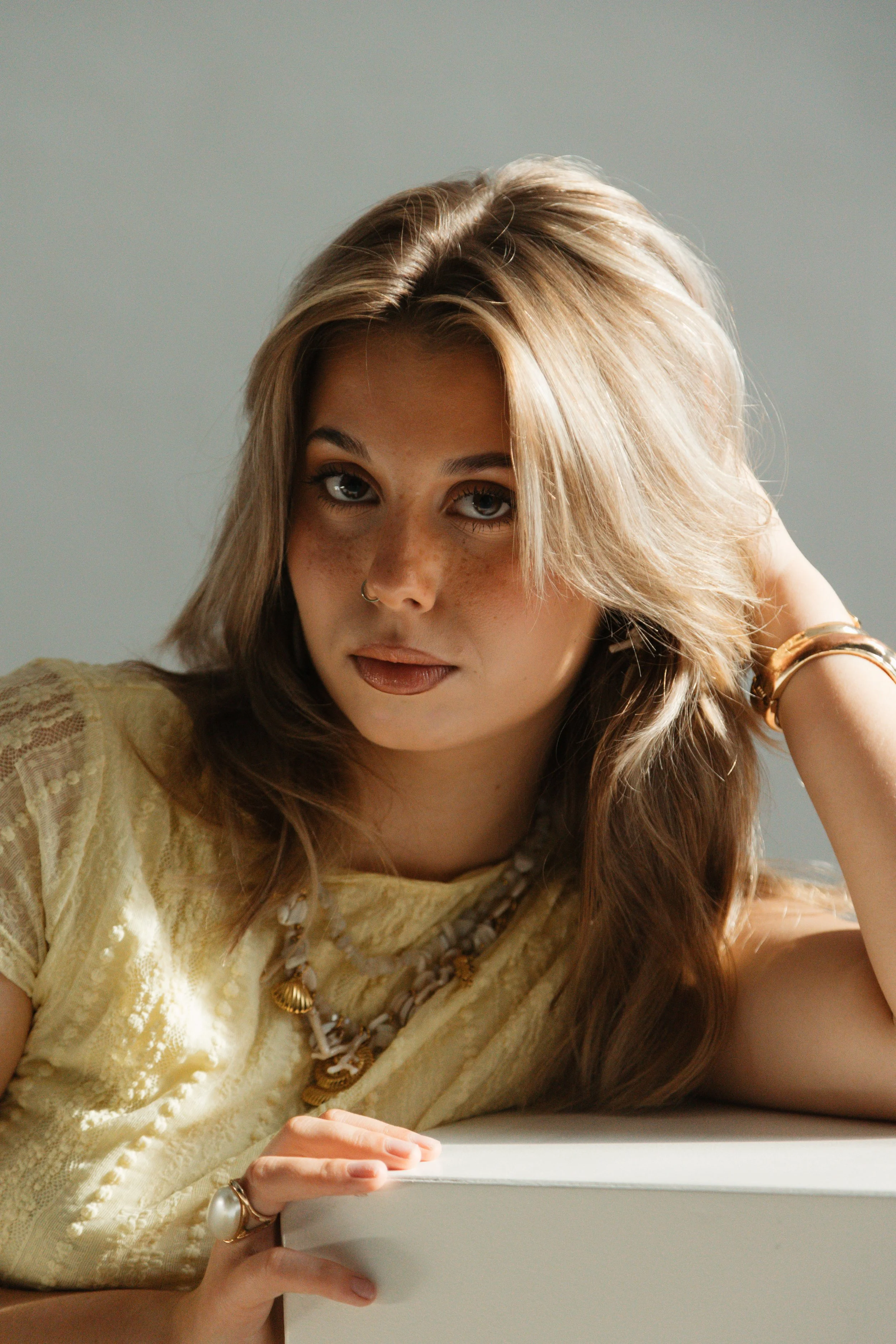 A person holding a bouquet of colorful flowers while sitting with their legs crossed, with part of their beige clothing and bare skin visible.