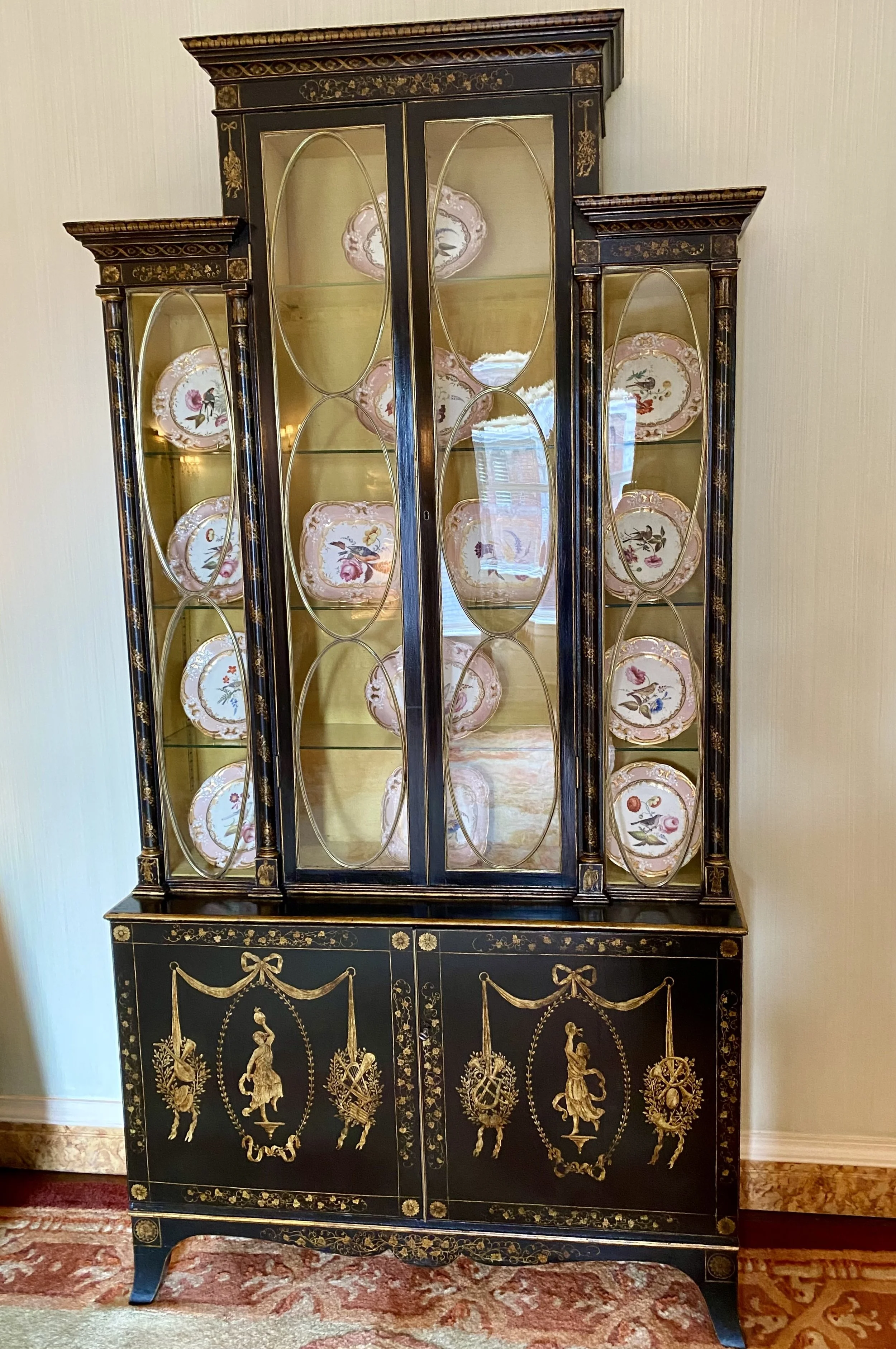 Fine and Rare English Japanned China Cabinet, decorated with gilt classical figures and musical instruments on a black background; the top section with elongated oval brass astragals, Late 18th / Early 19th Century (48 ¾ inches wide x 16 ¼ inches dee