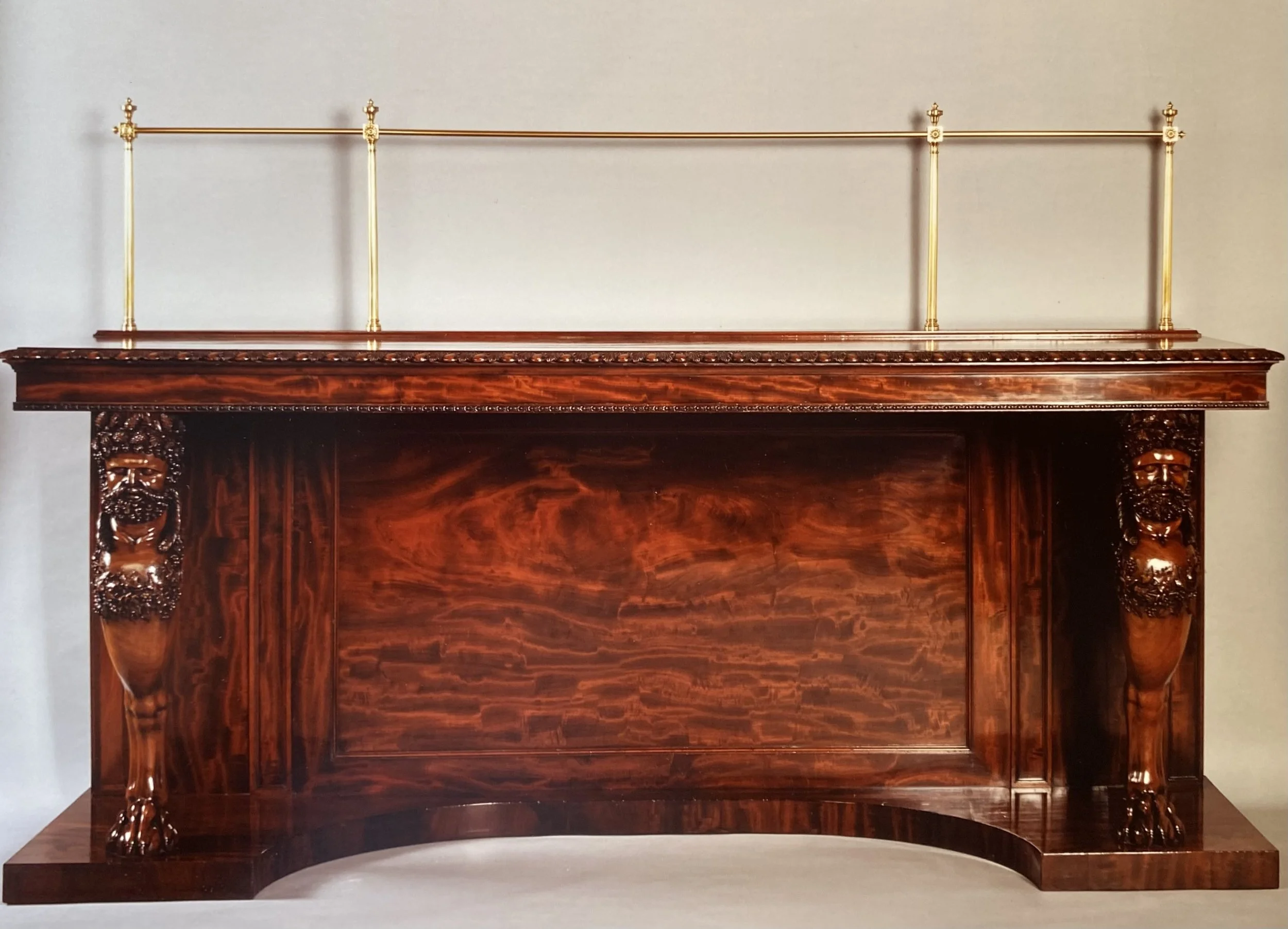Fine Regency Carved Mahogany Sideboard, with original brass gallery and supported on Bacchic monopodia (87 ¾ inches wide x 27 ¼ inches deep x 37 ½ inches high (56 to top of brass rail) Provenance: Philip Hewat-Jaboor, London, 1988