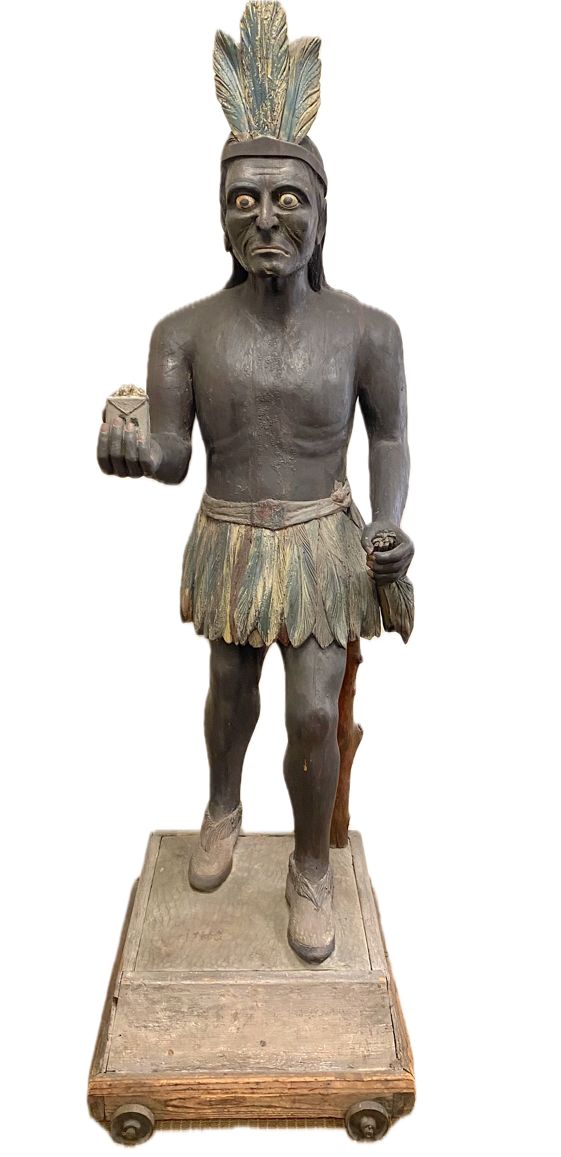 American Carved & Polychromed Wood Figure of a Cigar Store Indian Brave, Late 19th c.;
The dark-skinned figure stands with a package of tobacco in his right outstretched hand and tobacco leaves in his left hand, with prominent nose; Traces of origina