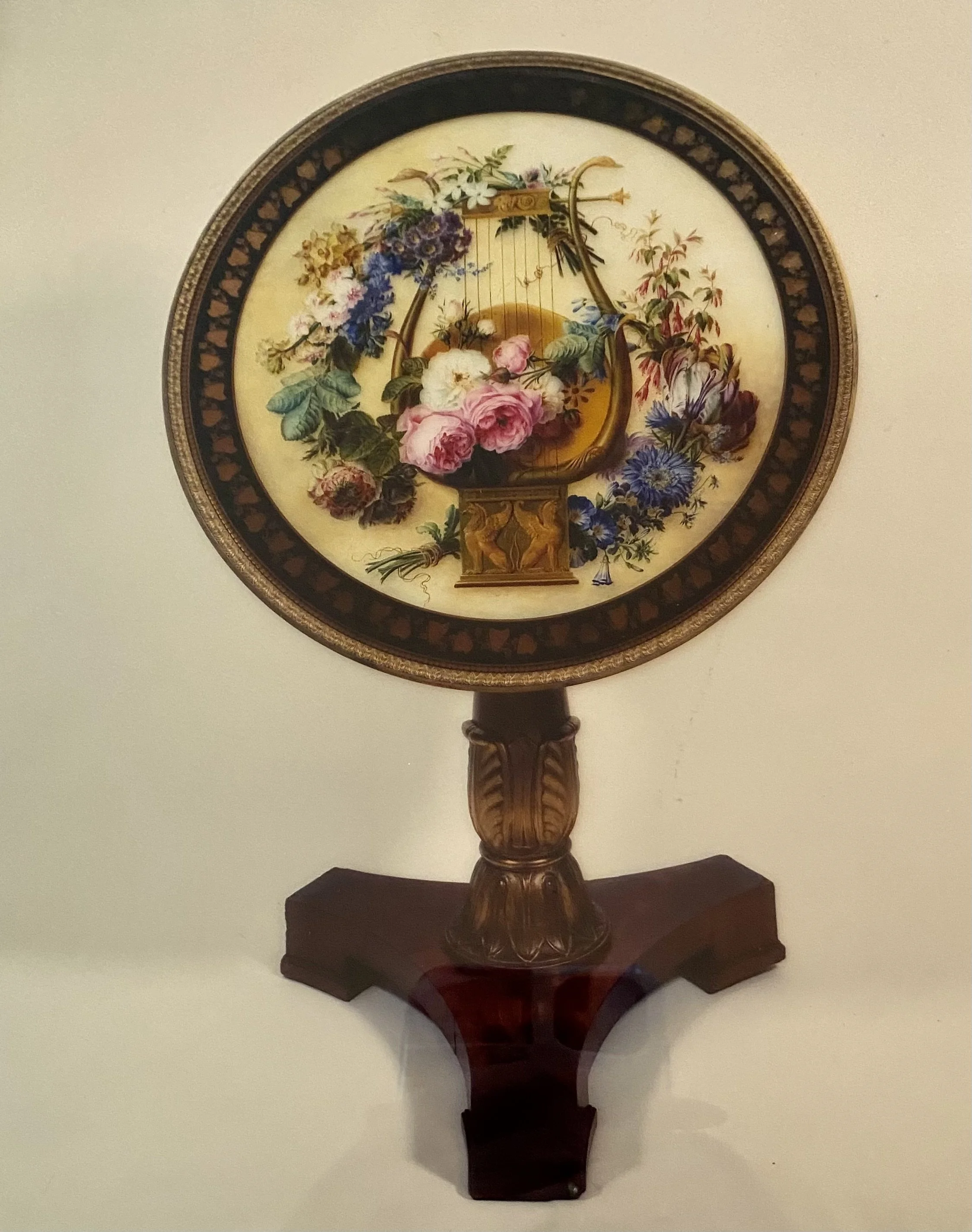 Charles X Tilt Top Gueridon, with a triangular base, a singular carved and gilded wood column and a circular top decorated in eglomise with floral decoration surrounded by a border of gold ivy leaves on a black ground (31 ¼ inches diameter x 32 inche