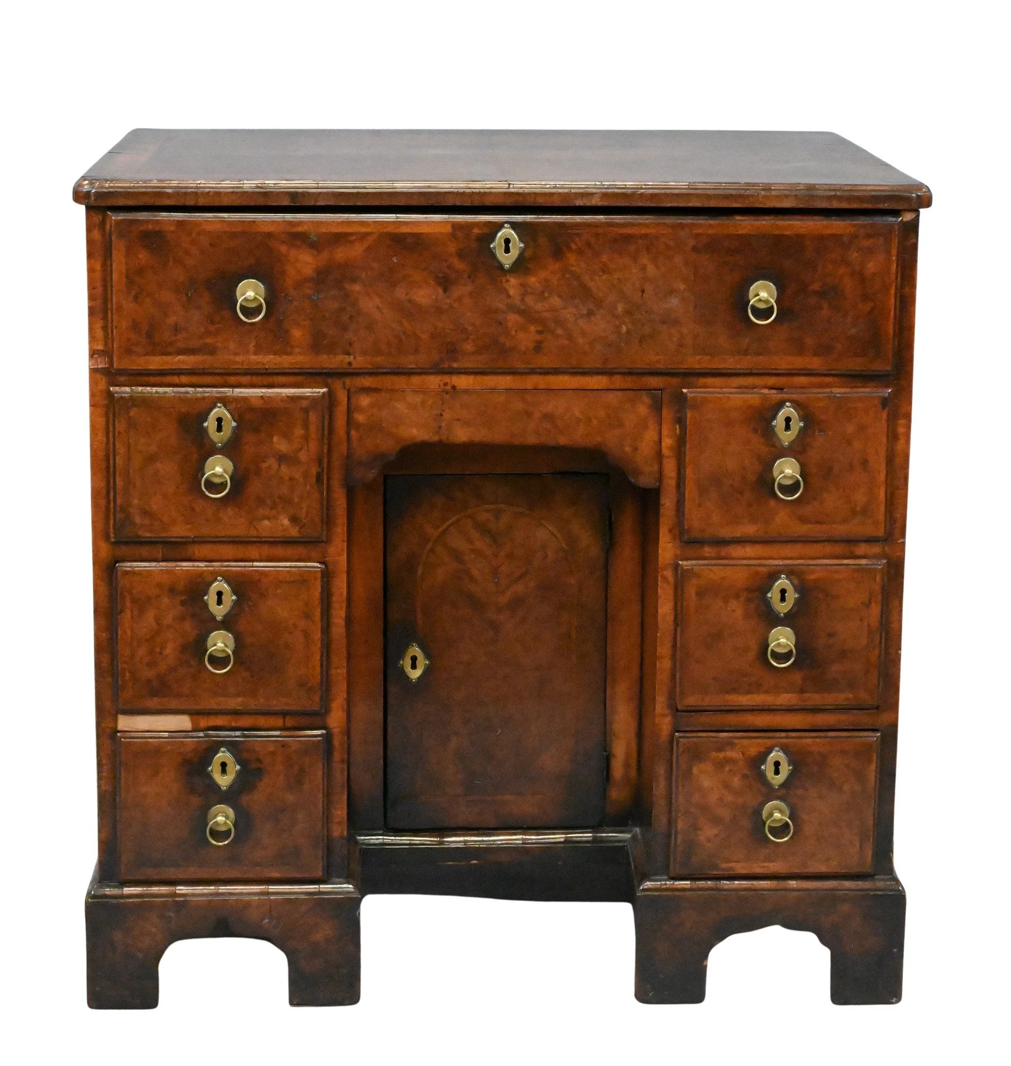 George I Burl Walnut Kneehole Desk
having rectangular top with feather-banded inlay above a long drawer opening to a fitted writing surface and compartments, over a drawer and arched kneehole recess fitted with a cupboard door flanked by three drawer