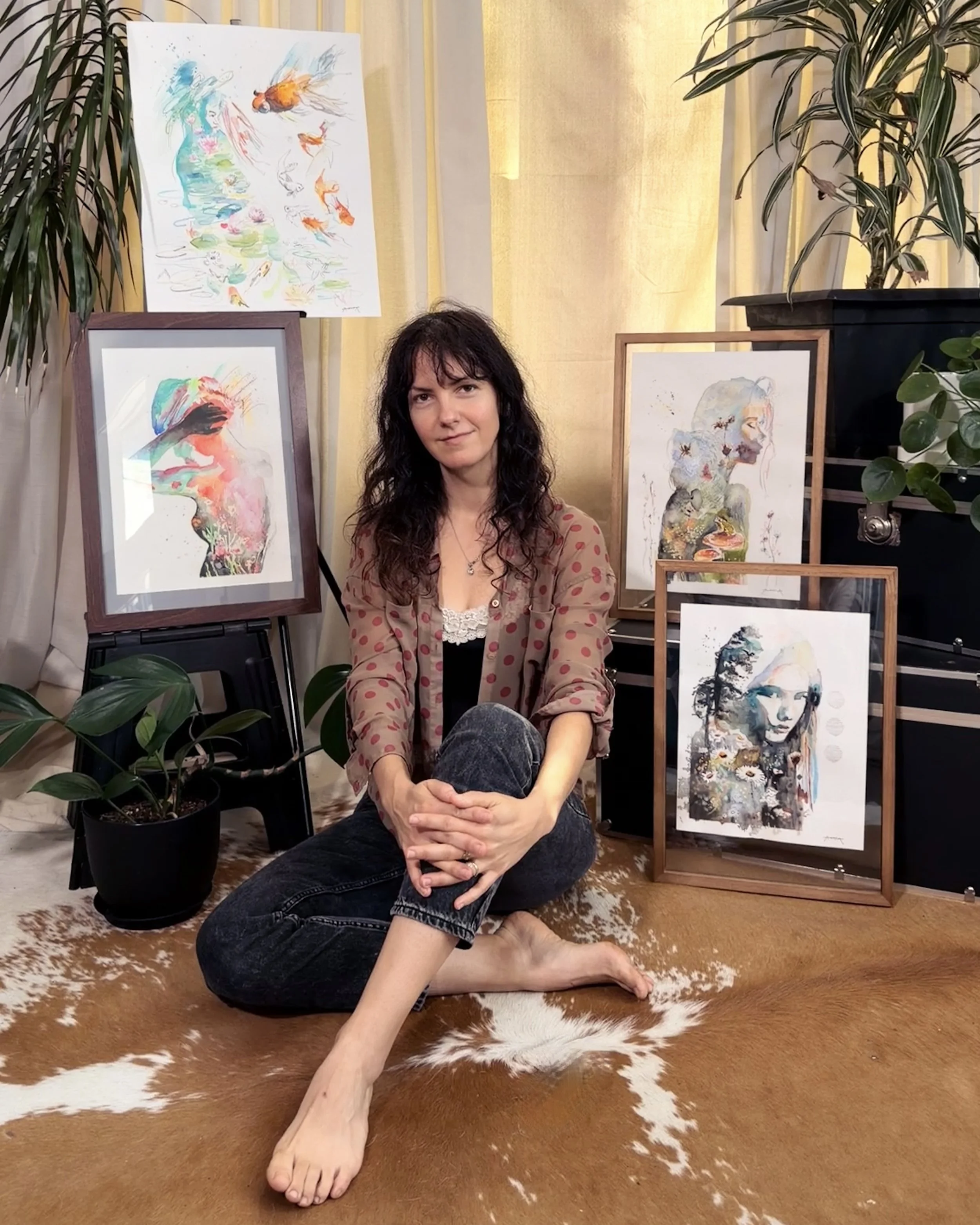 Woman sitting on a cowhide rug in front of artwork, plants, and a gold curtain.