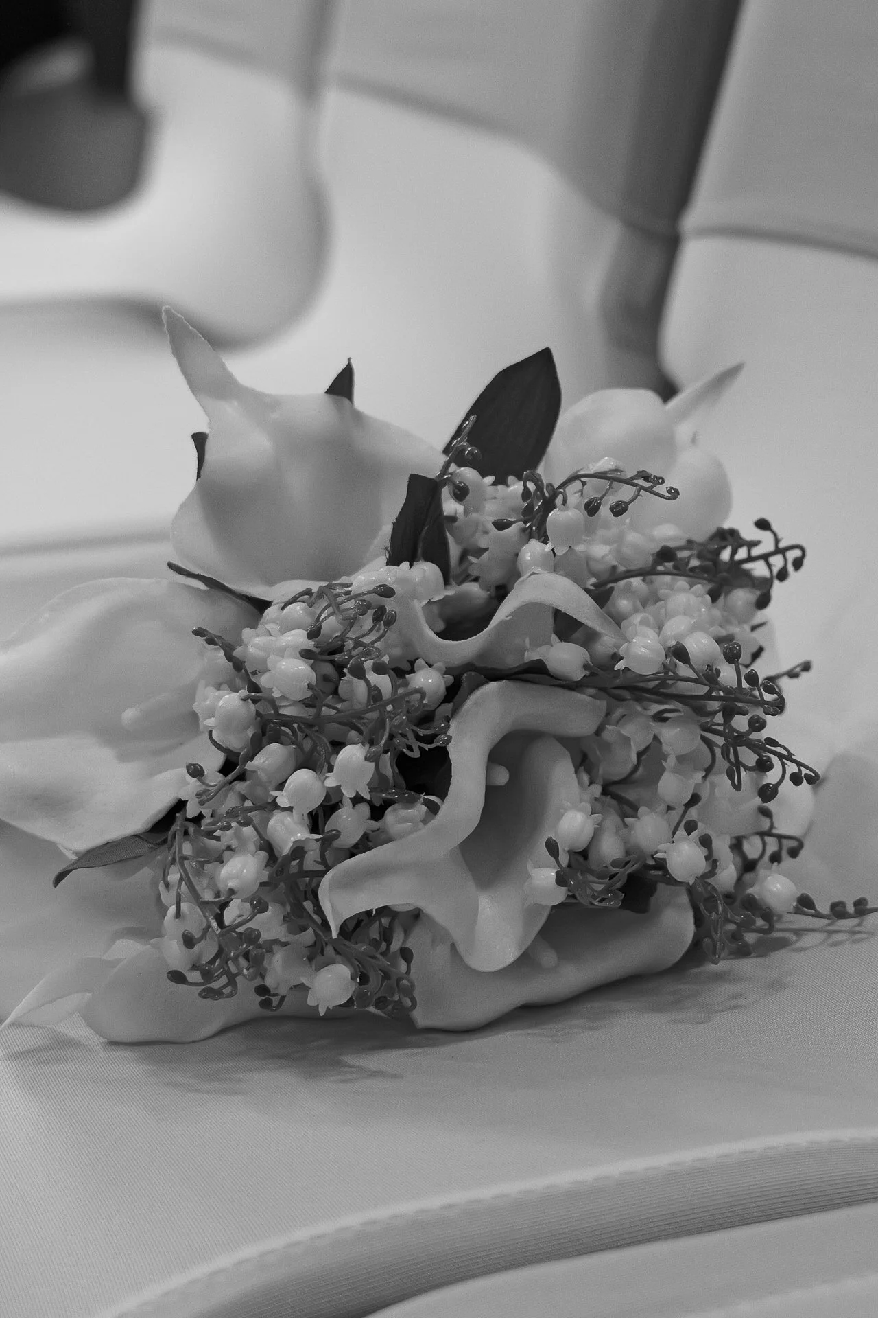 A woman with glasses and pearl-studded hair holding a champagne glass in a dimly lit setting with purple lighting.