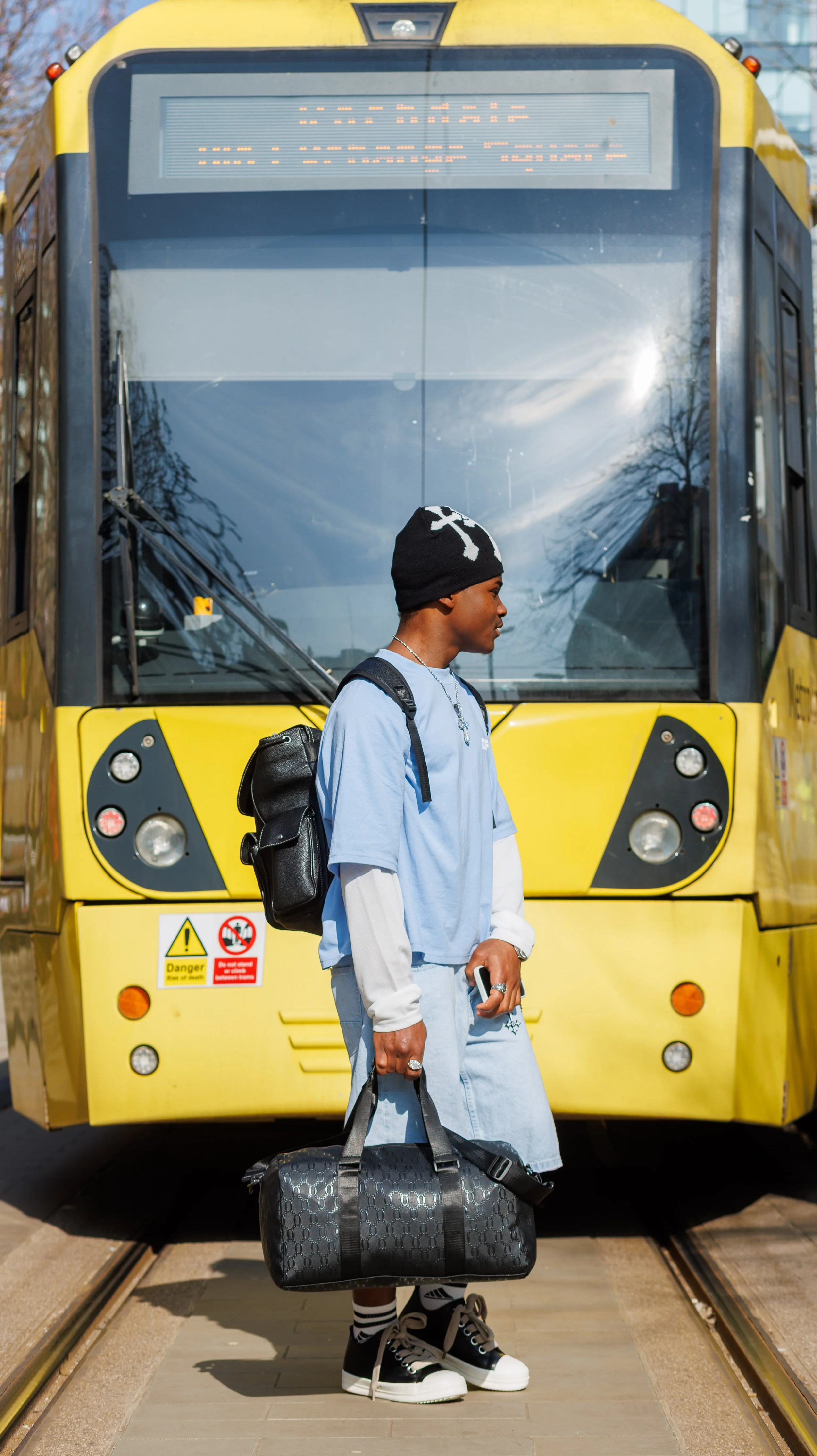 A woman wearing traditional African clothing and a blue headwrap, looking down.