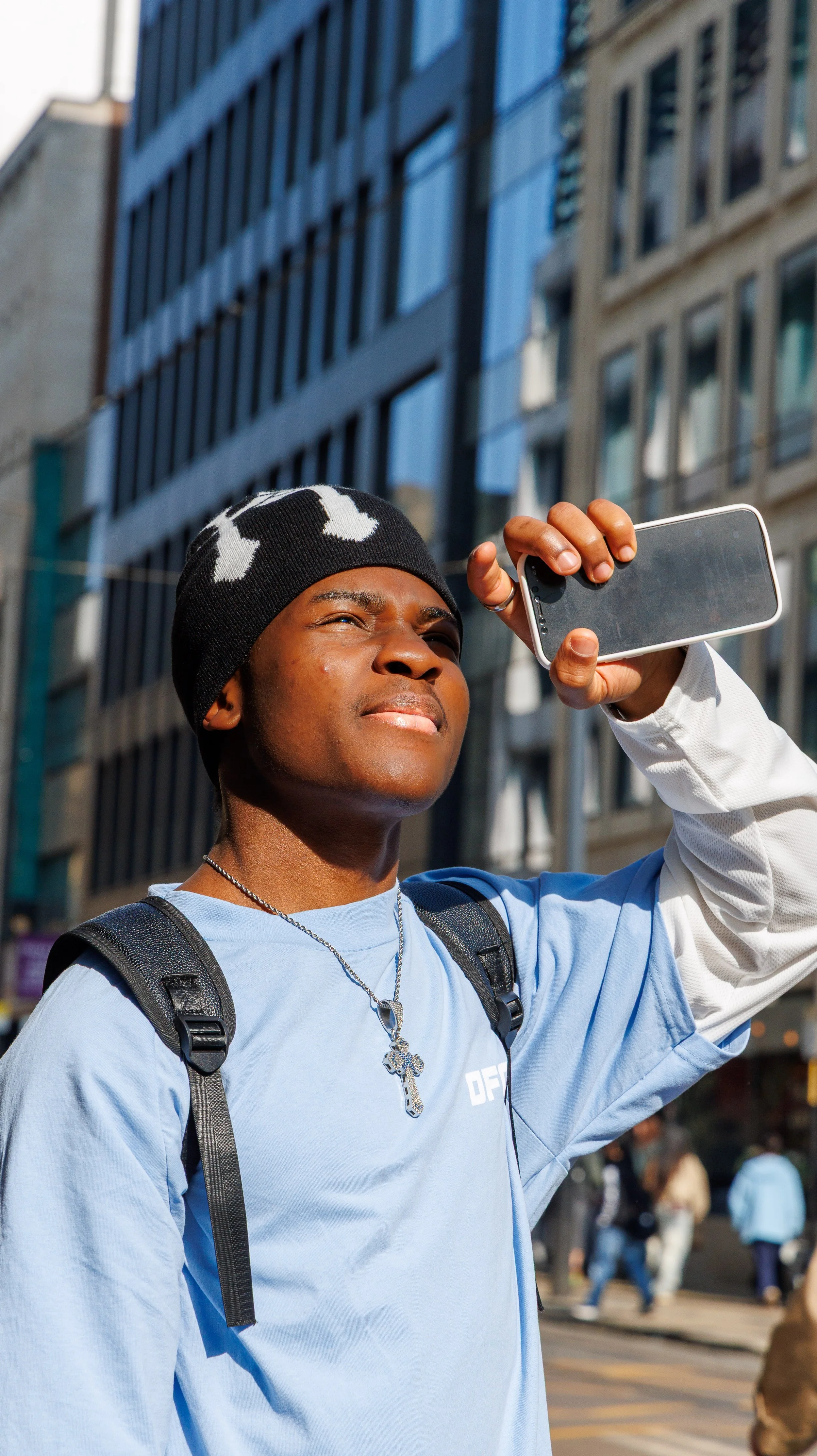 A woman with long, curly brown hair looks at her reflection through a circular mirror. She is wearing a burgundy dress with intricate gold and silver embroidery.