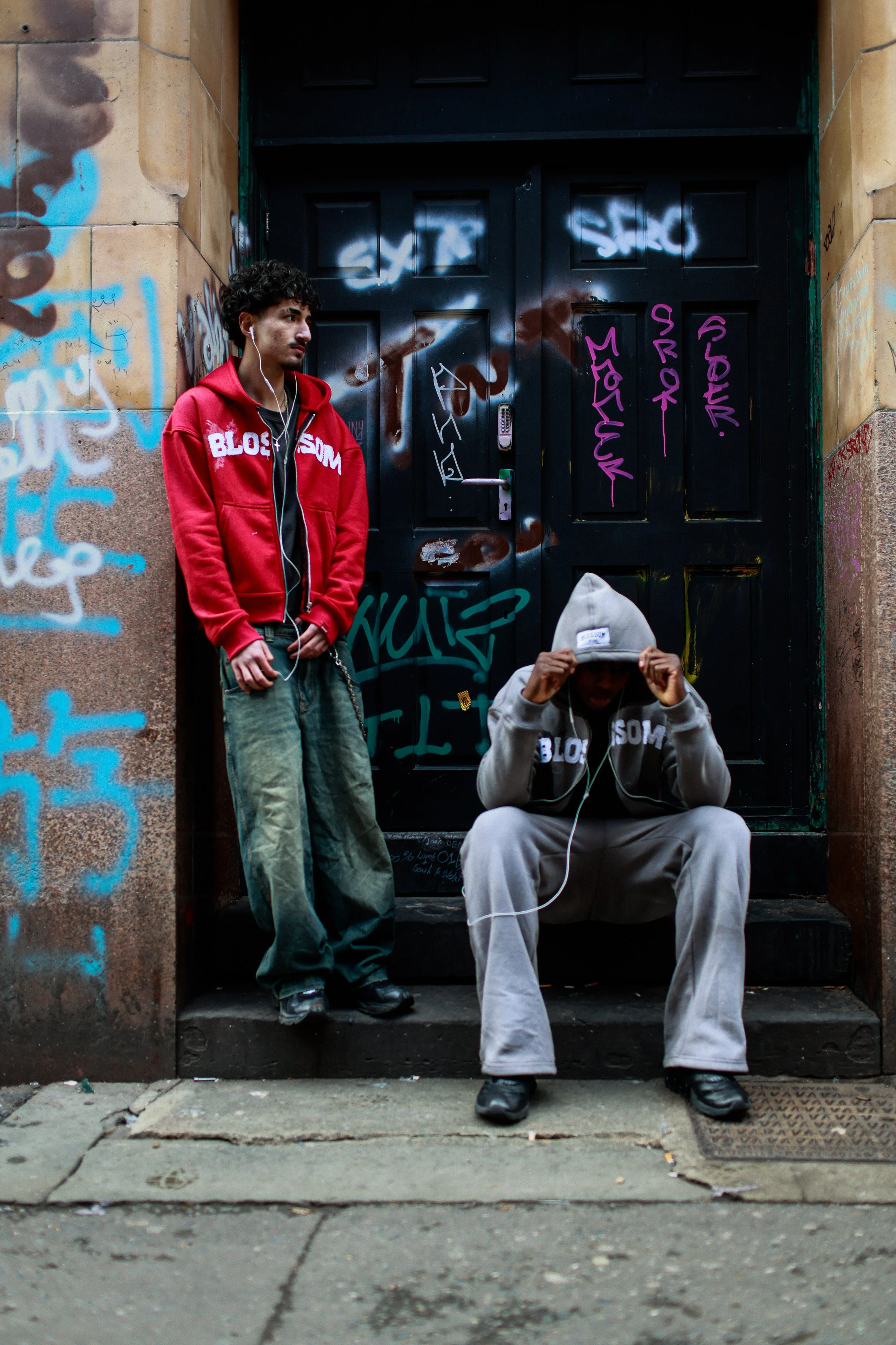 A young man performing on stage with a microphone and electric guitar, wearing a black shirt, under dim stage lighting.