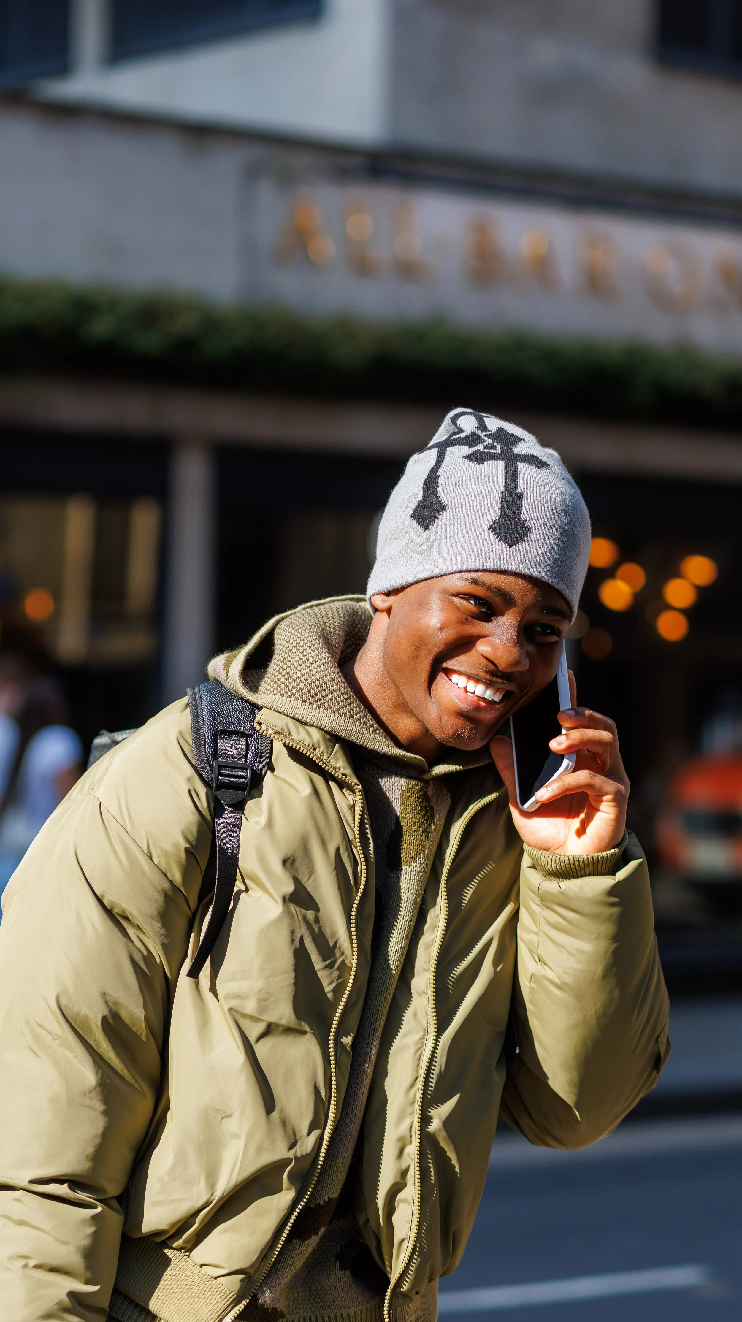 A woman wearing traditional African attire with a large, elaborately wrapped headwrap in navy blue, adorned with jewelry including red beaded necklaces and earrings, and a blue and gold patterned dress.