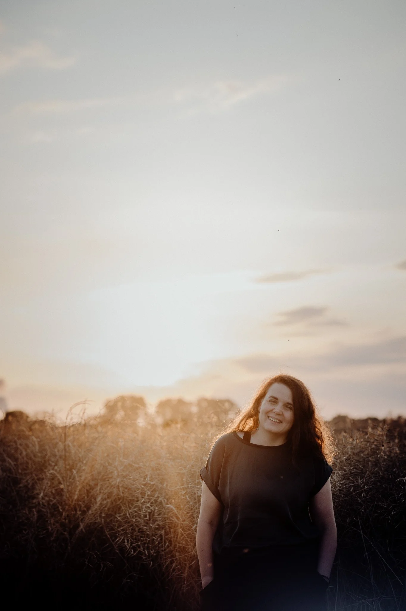 Frau lacht zum Sonnenuntergang in die Kamera