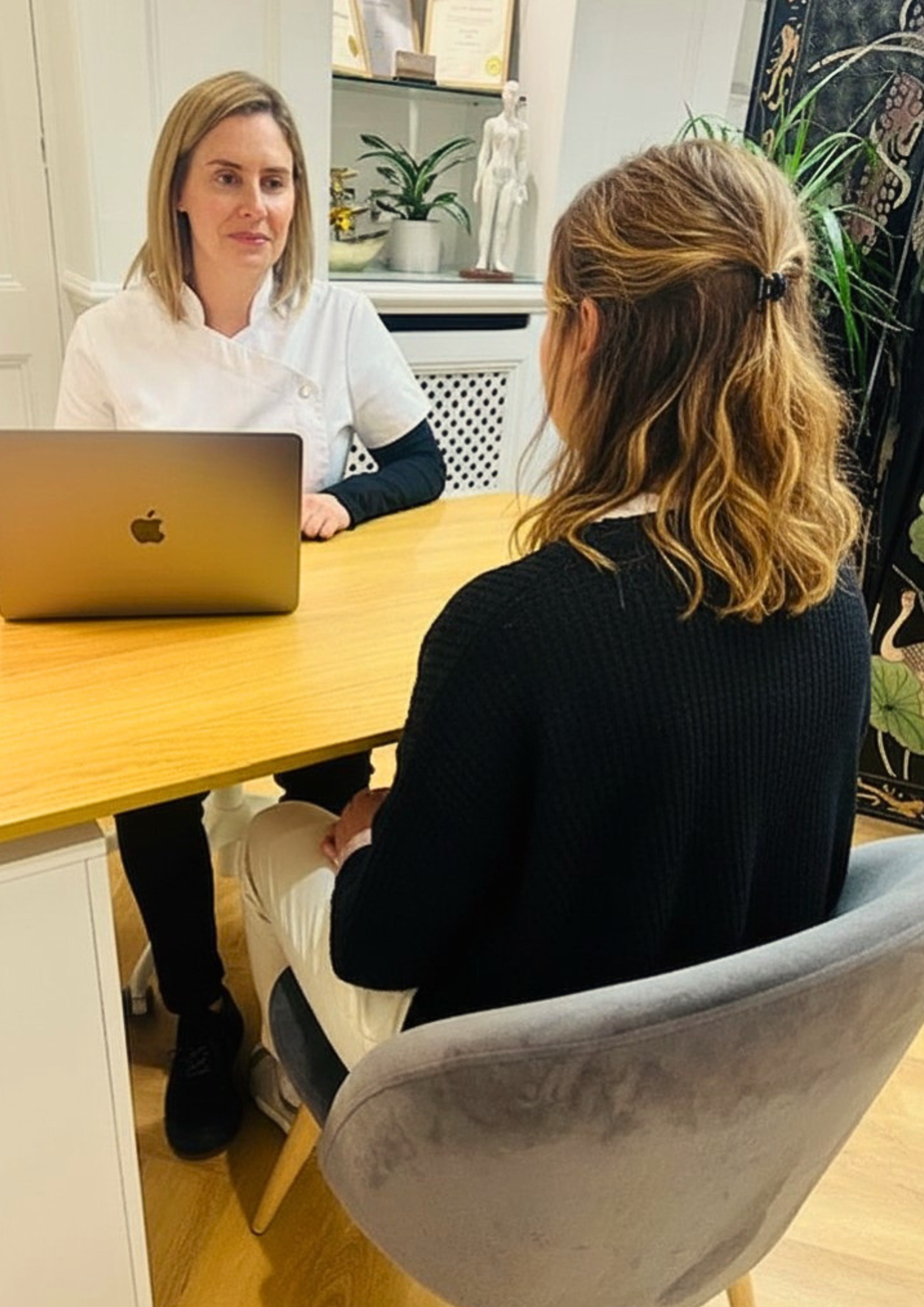 Nickila Robertsson, licensed acupuncturist and member of the British Acupuncture Council consulting with a patient at NRQi Studio in Winchmore Hill, London N21