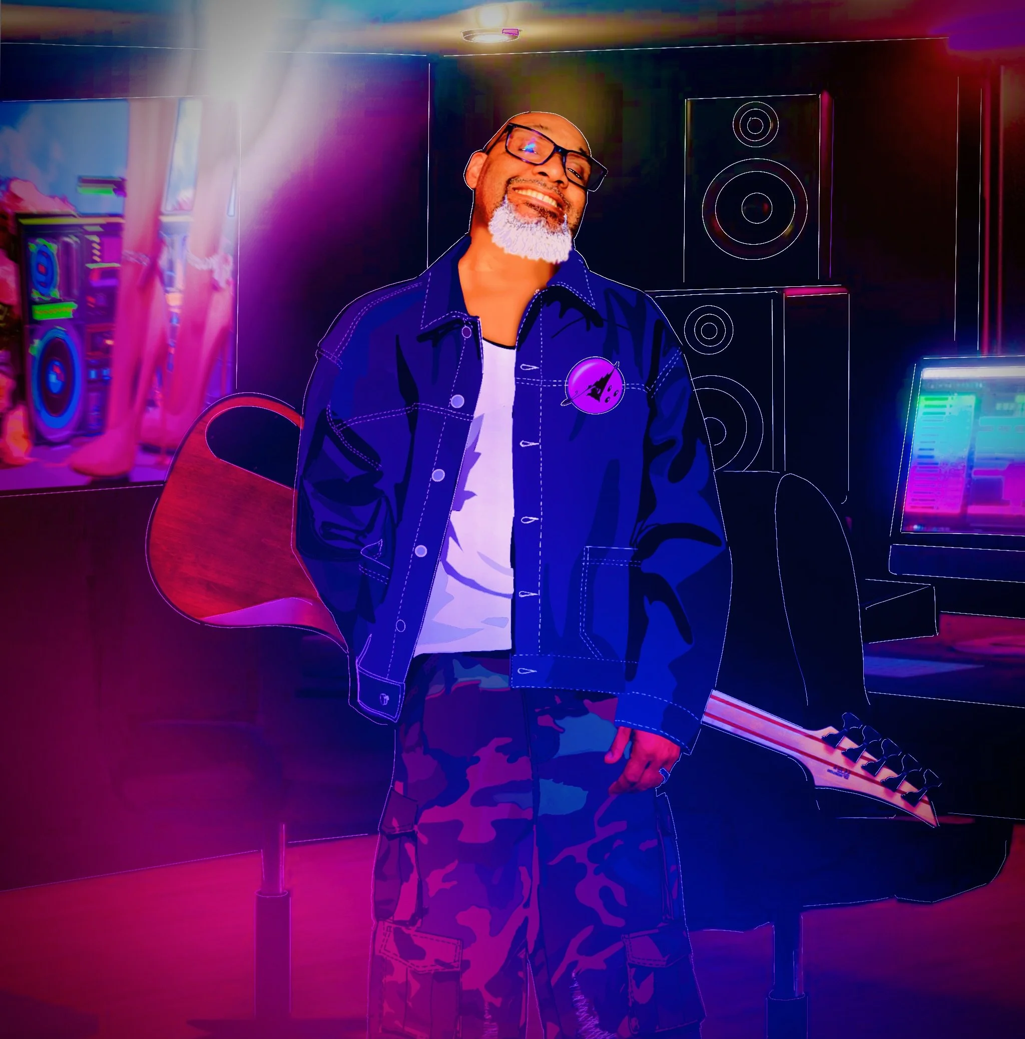 A man with glasses and a gray beard smiling in a music studio with a guitar, speakers, and a colorful computer screen.