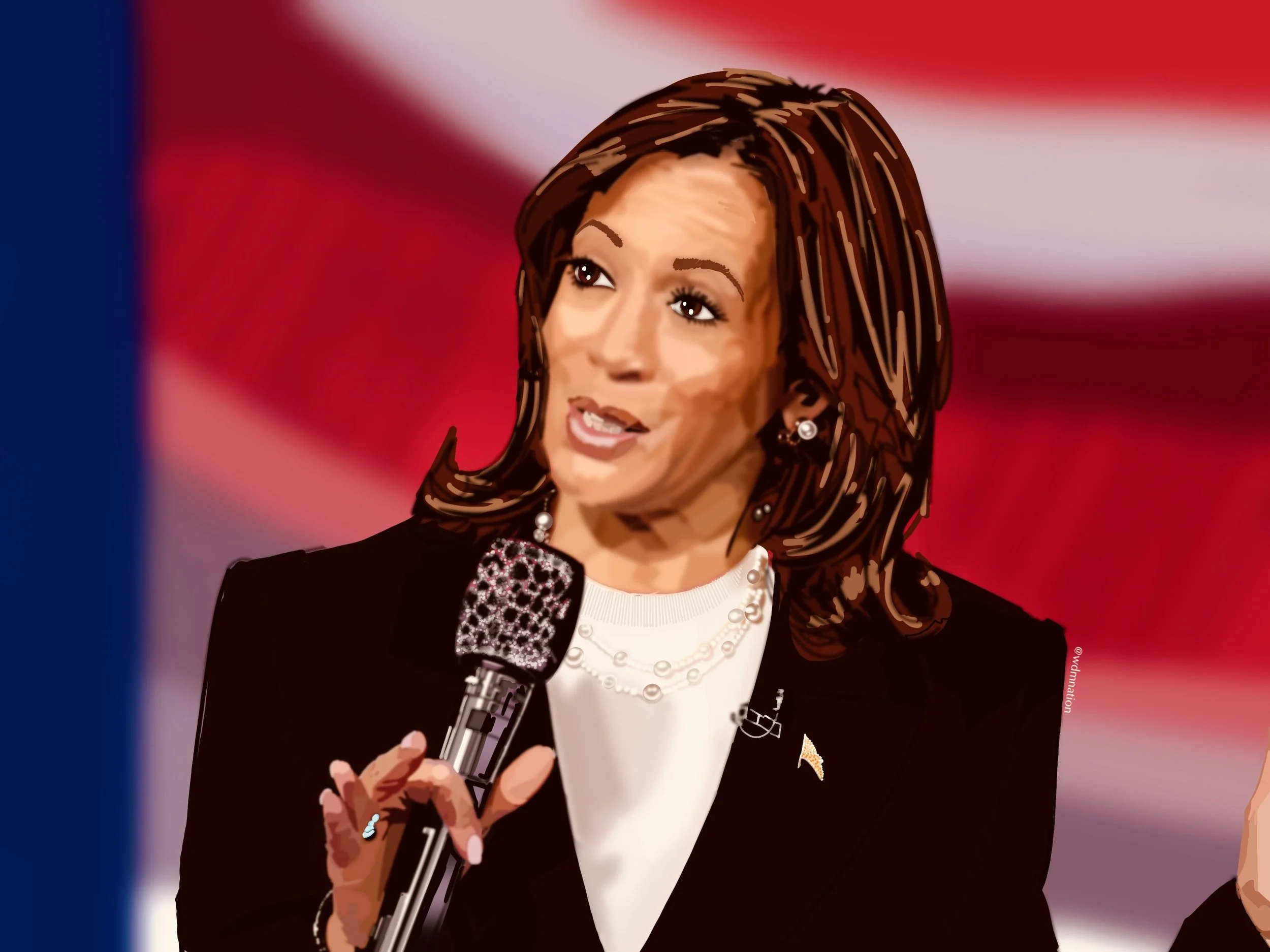 A woman with shoulder-length brown hair speaking into a microphone, wearing a black blazer, white top, pearl necklace, and earrings, with an American flag in the background.