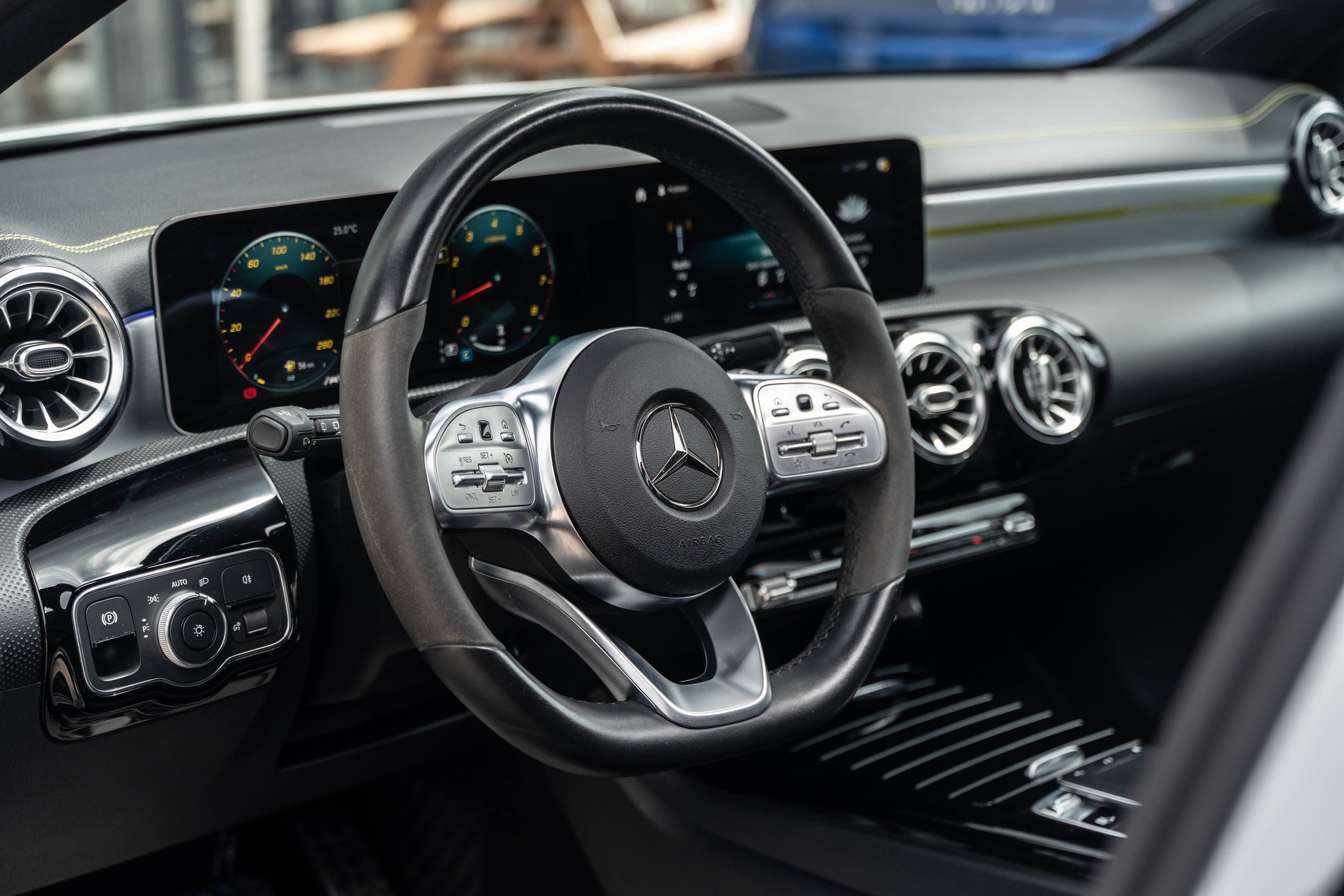 Interieur van een Mercedes-Benz auto, inclusief stuur, instrumentenpaneel, en luchtcirculatie-openingen.