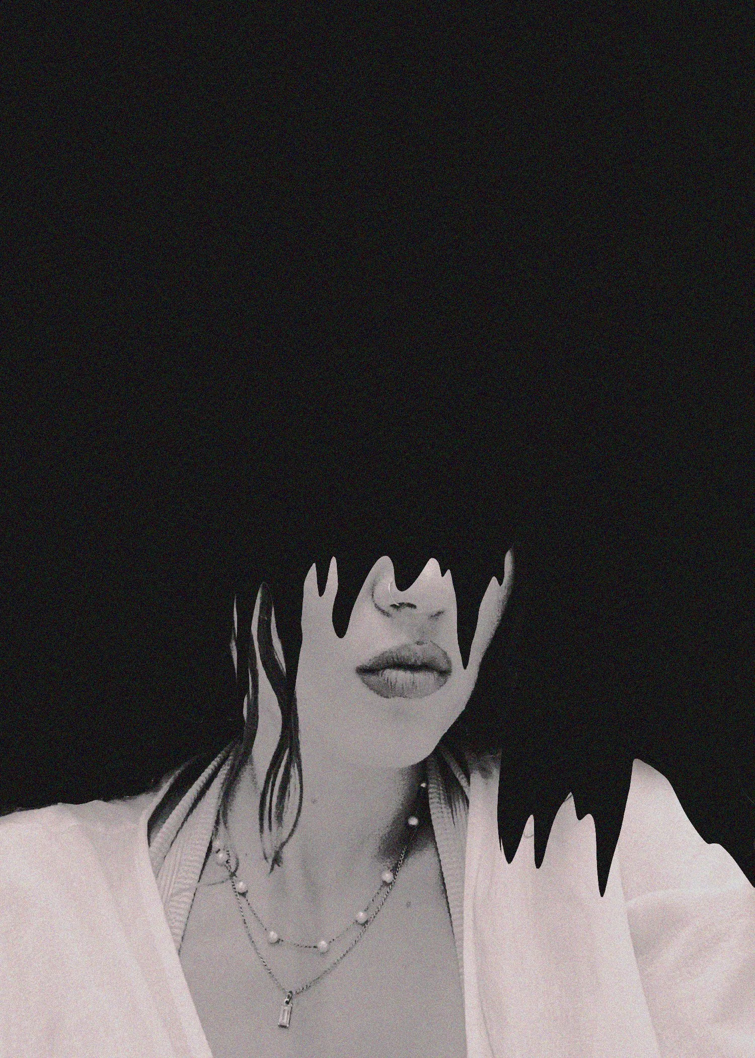 A black and white photo of a woman's face with curly hair. Only her lips and part of her nose are visible, as her eyes and eyebrows are covered by dark, eye-covering hair or a hat. She is wearing layered necklaces and a light-colored top.