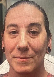Close-up of a person with long dark hair, gauged ears, and a neutral expression.