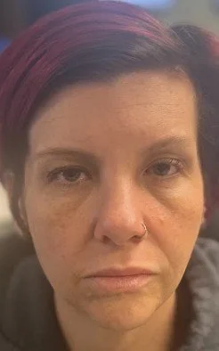 Close-up of a woman with short red hair and a nose ring, looking directly at the camera