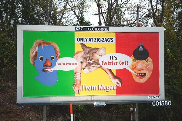 Colorful billboard with three characters: a blue face with red hair on the left, a cat in the middle, and an exaggerated face with a black hat on the right. The text says, "ONLY AT ZIG-ZAG'S," "Fun For Everyone," "It's Twister Cat!" and "From Mgee."
