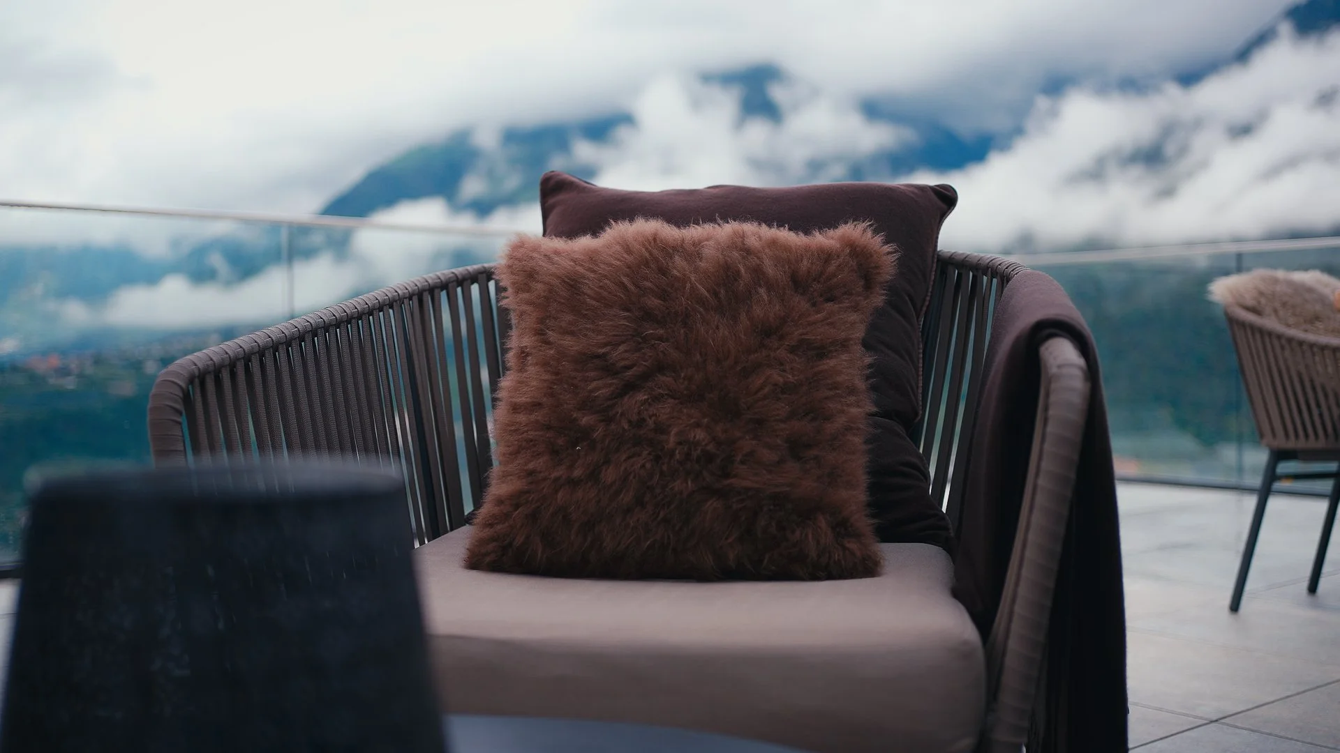 Seduta con cuscini di pelliccia su una terrazza con vista sulle montagne.